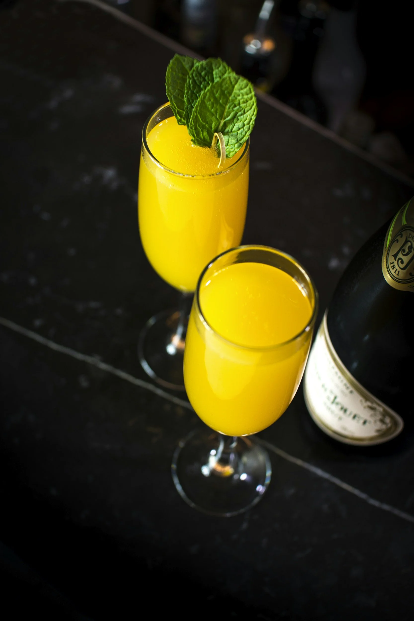 Two mimosas, on the bar counter with a bottle partially visible at Papito in Hayes Valley