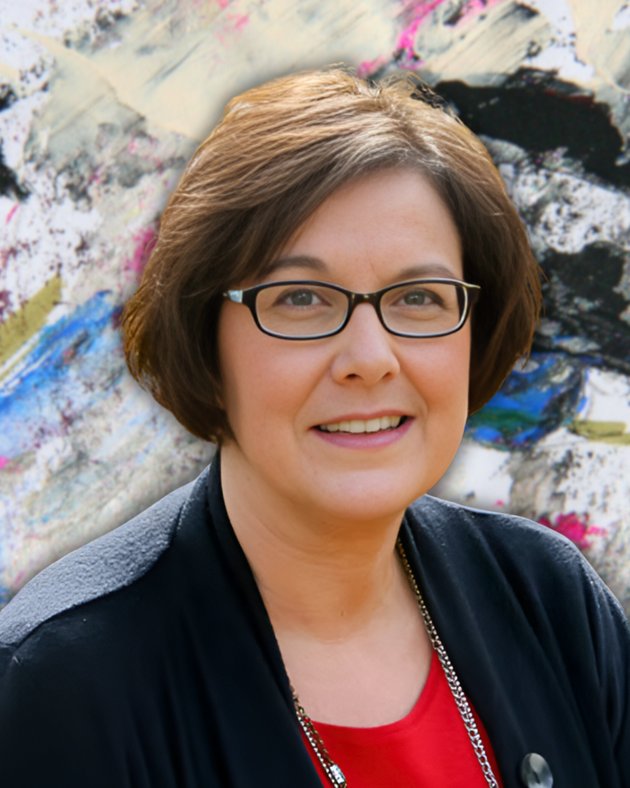 A woman with short brown hair wearing glasses, a black jacket, and a red top, smiling in front of an abstract colorful background.