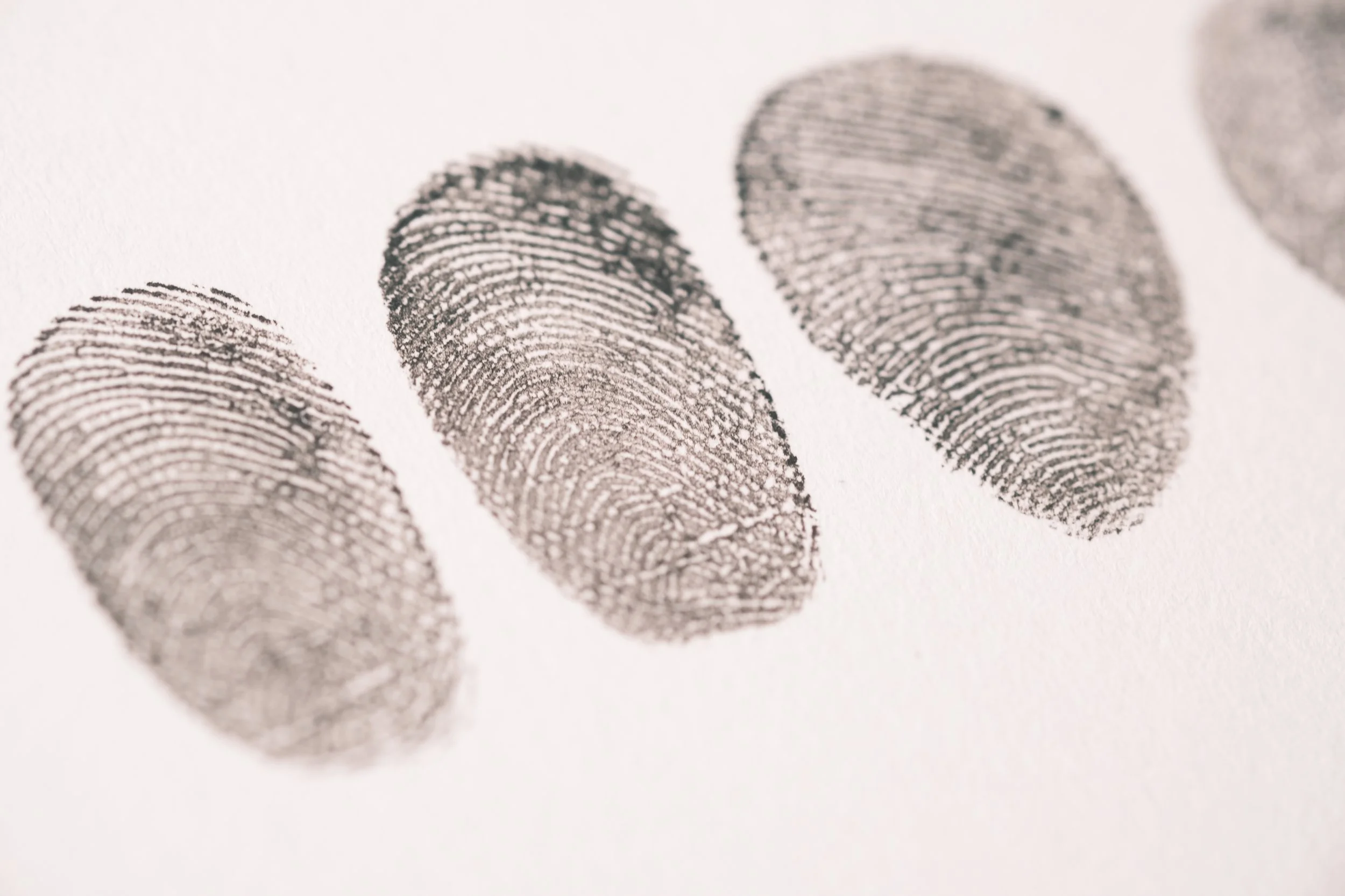 Close-up view of three black fingerprint impressions on white paper.