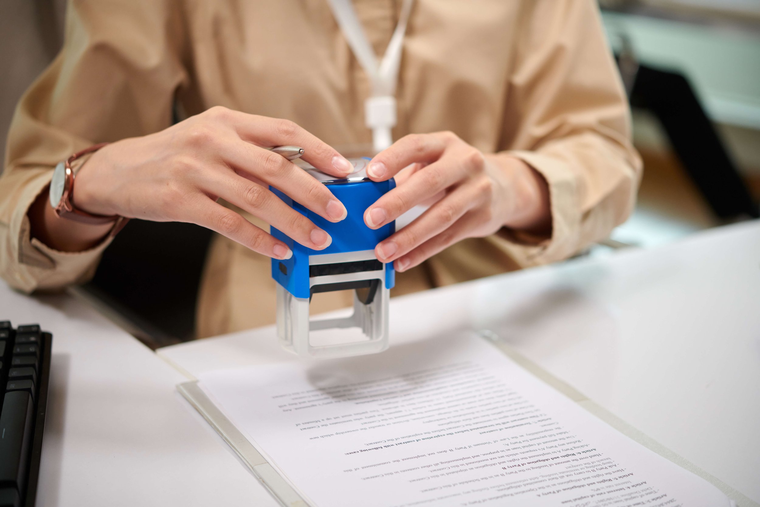 Person pressing a stamp onto an official document at an office desk.