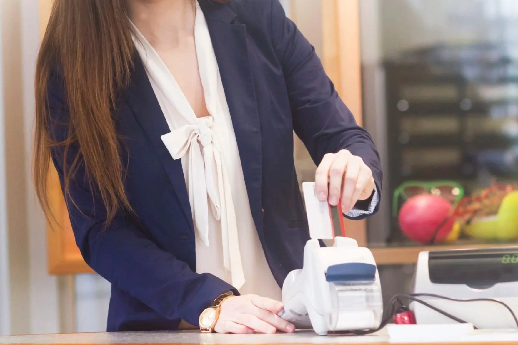 A woman is inserting a credit card into a payment terminal at a counter.