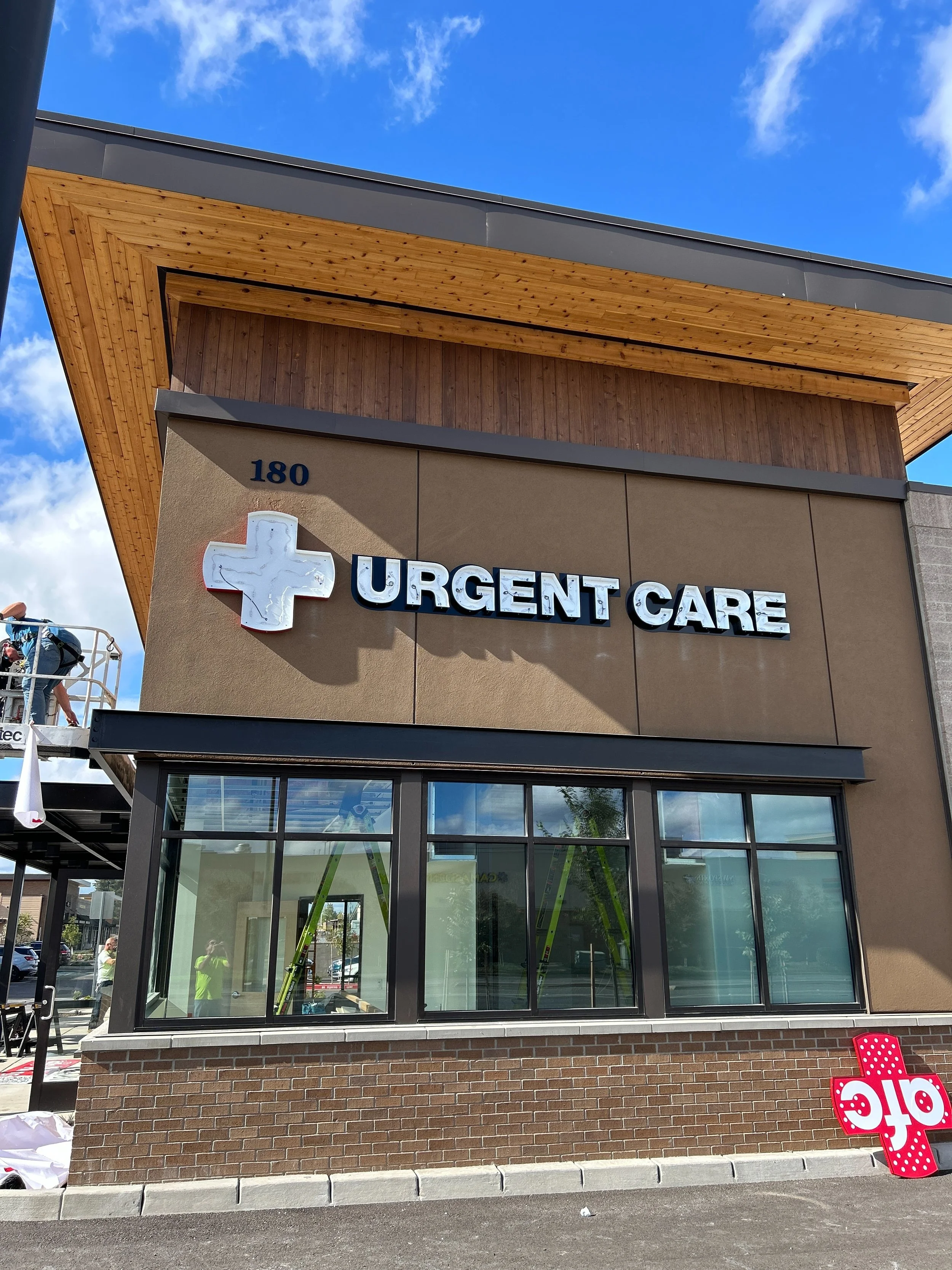 Exterior of a building with a sign reading 'Urgent Care' and a white medical cross symbol, with some construction activity visible nearby.