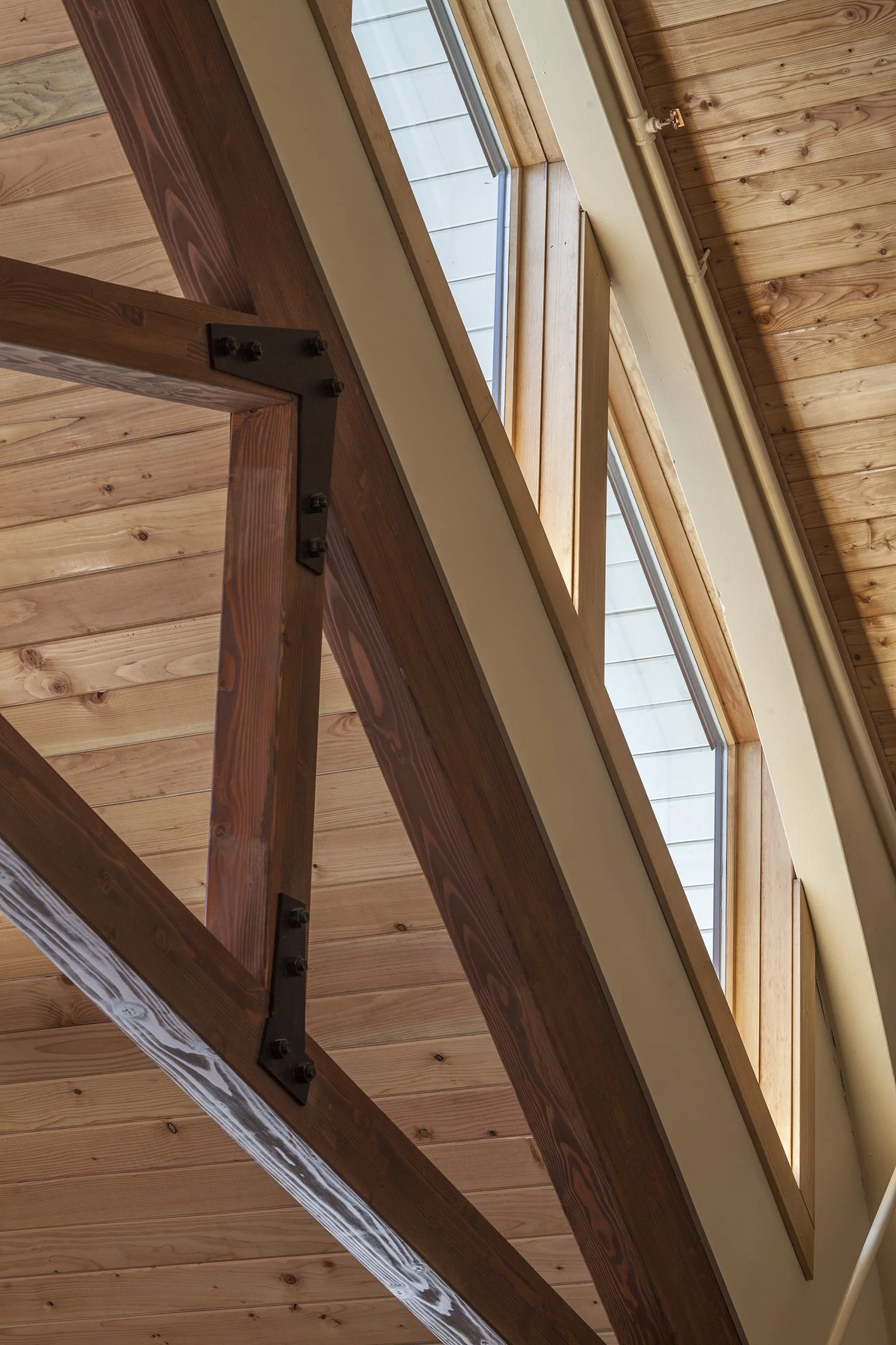 View of a wooden ceiling with skylights and exposed beams, showing the underside of a loft or upper floor in a house.
