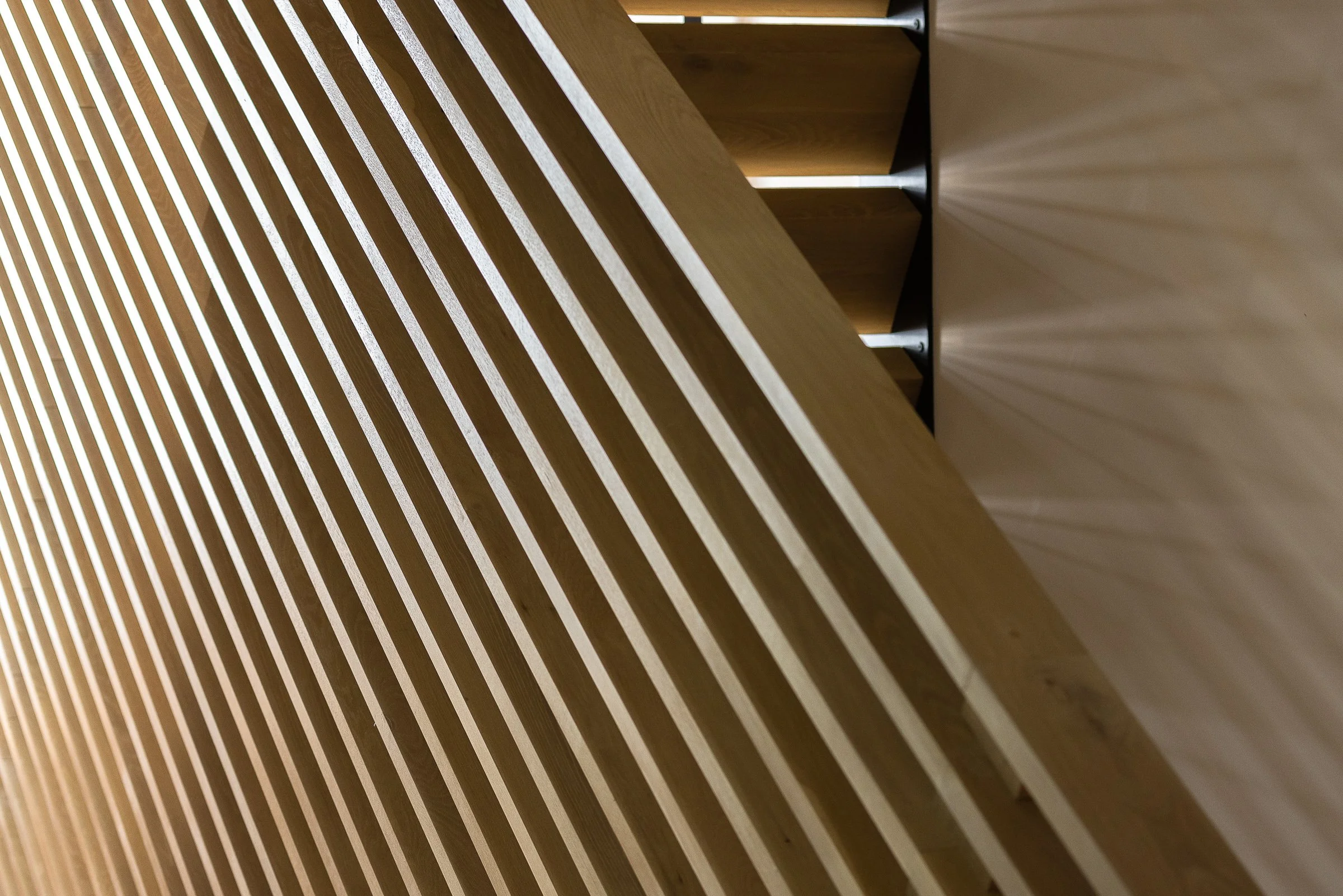 Close-up of a modern wooden slatted structure with angled design and shadows.