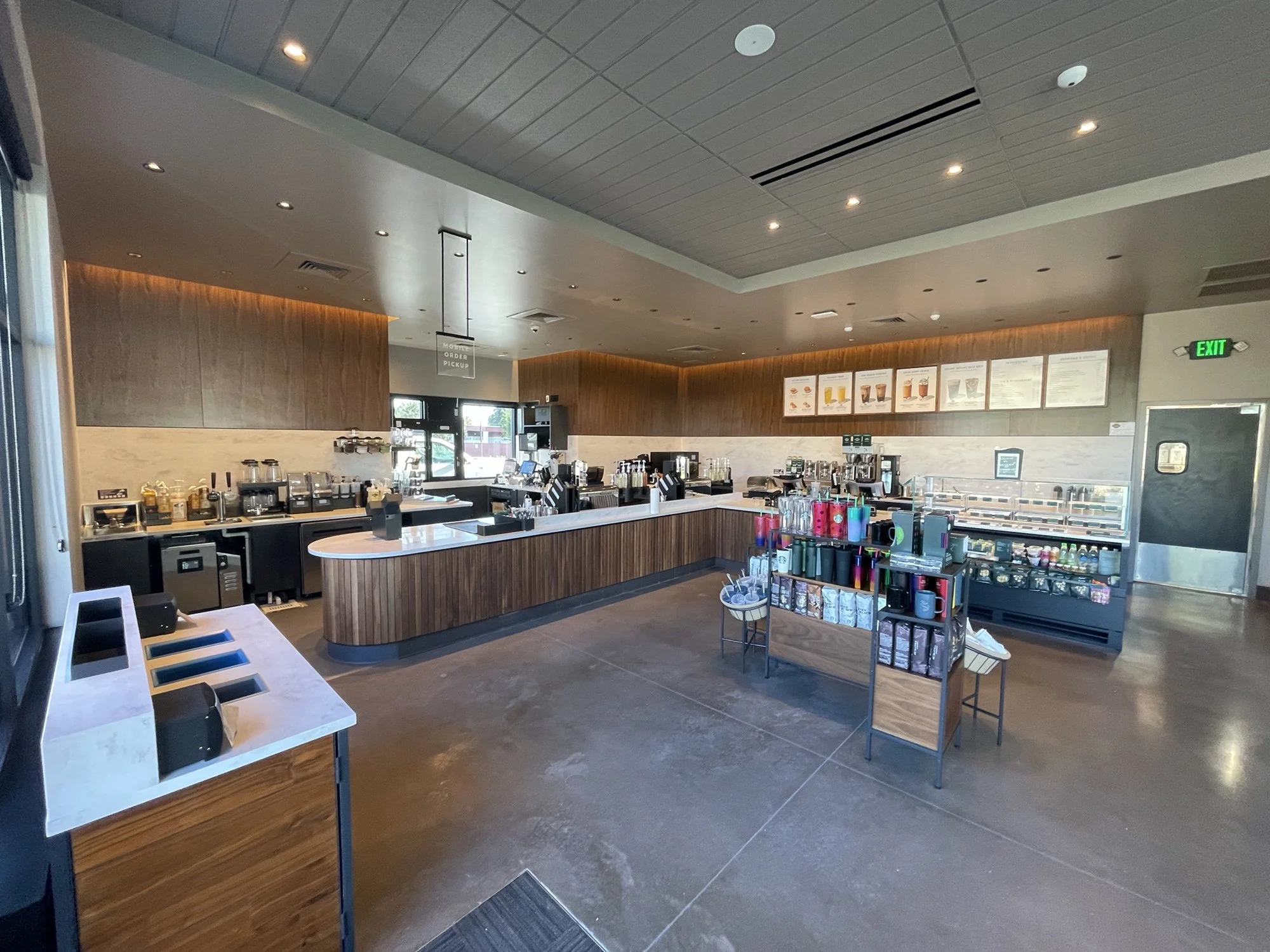 Empty coffee shop with a counter, display cases, and beverage equipment, bright lighting, and modern decor.