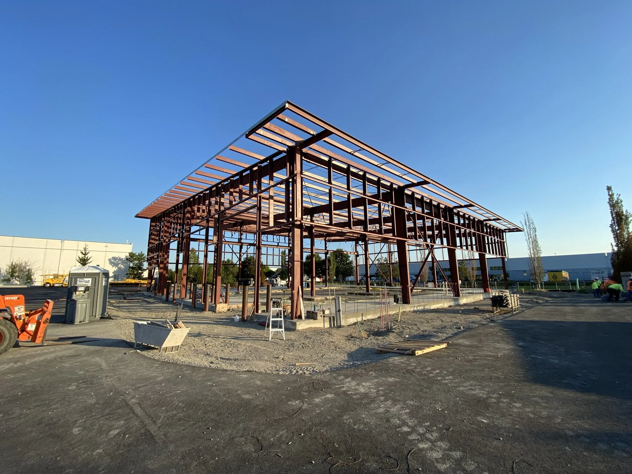 Under construction steel frame building at a construction site on a clear day with blue sky.