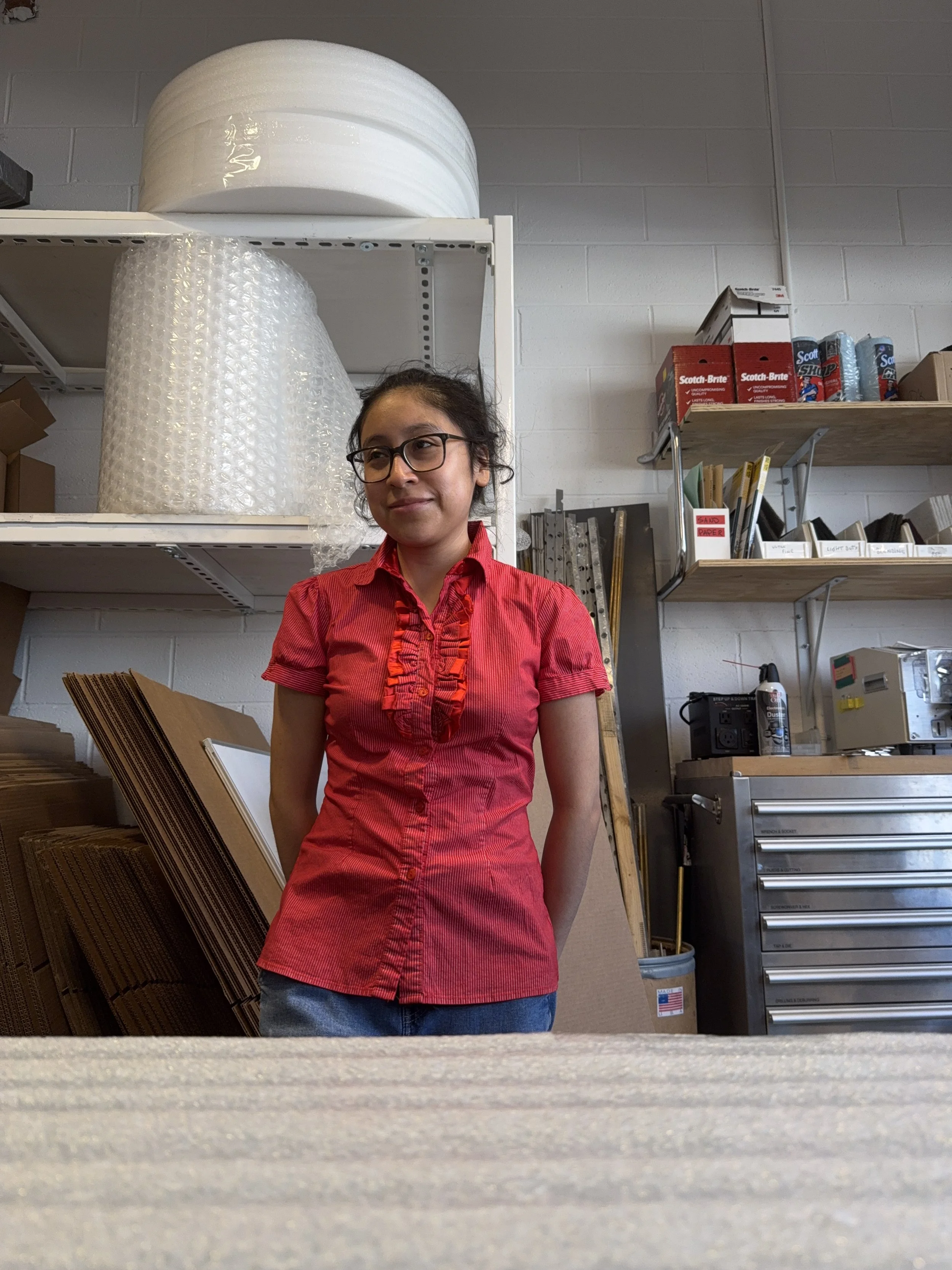 Iridian Castillo standing in front of a logistics workstation at work