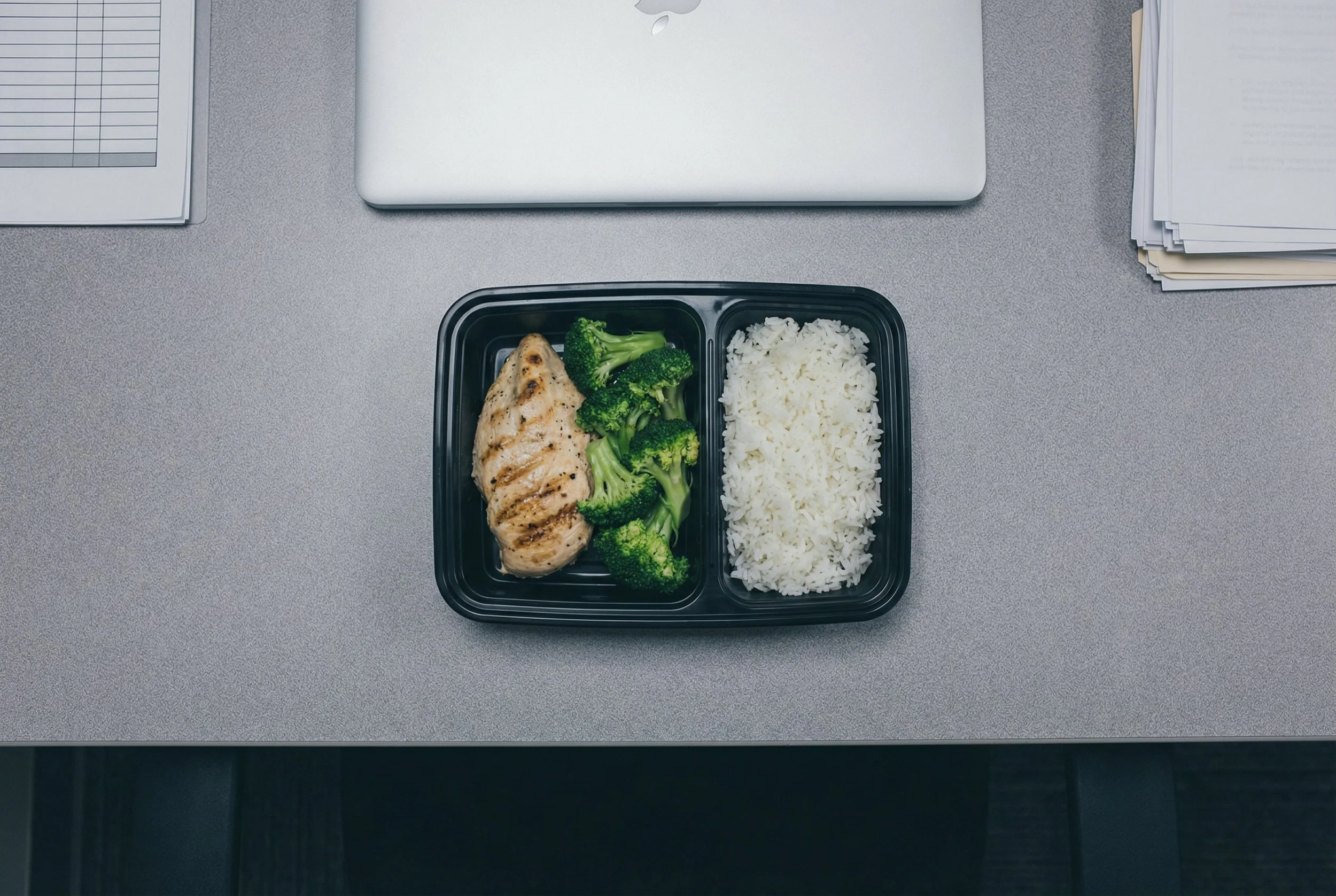 Basic chicken and rice meal prep container at office desk.