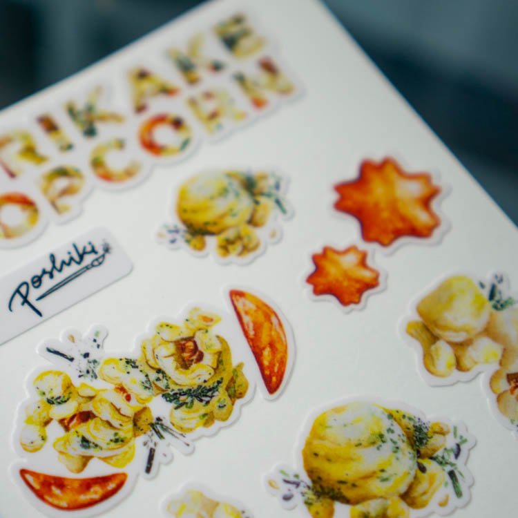 A close-up of watercolor stickers of kakimochi and furikake popcorn.