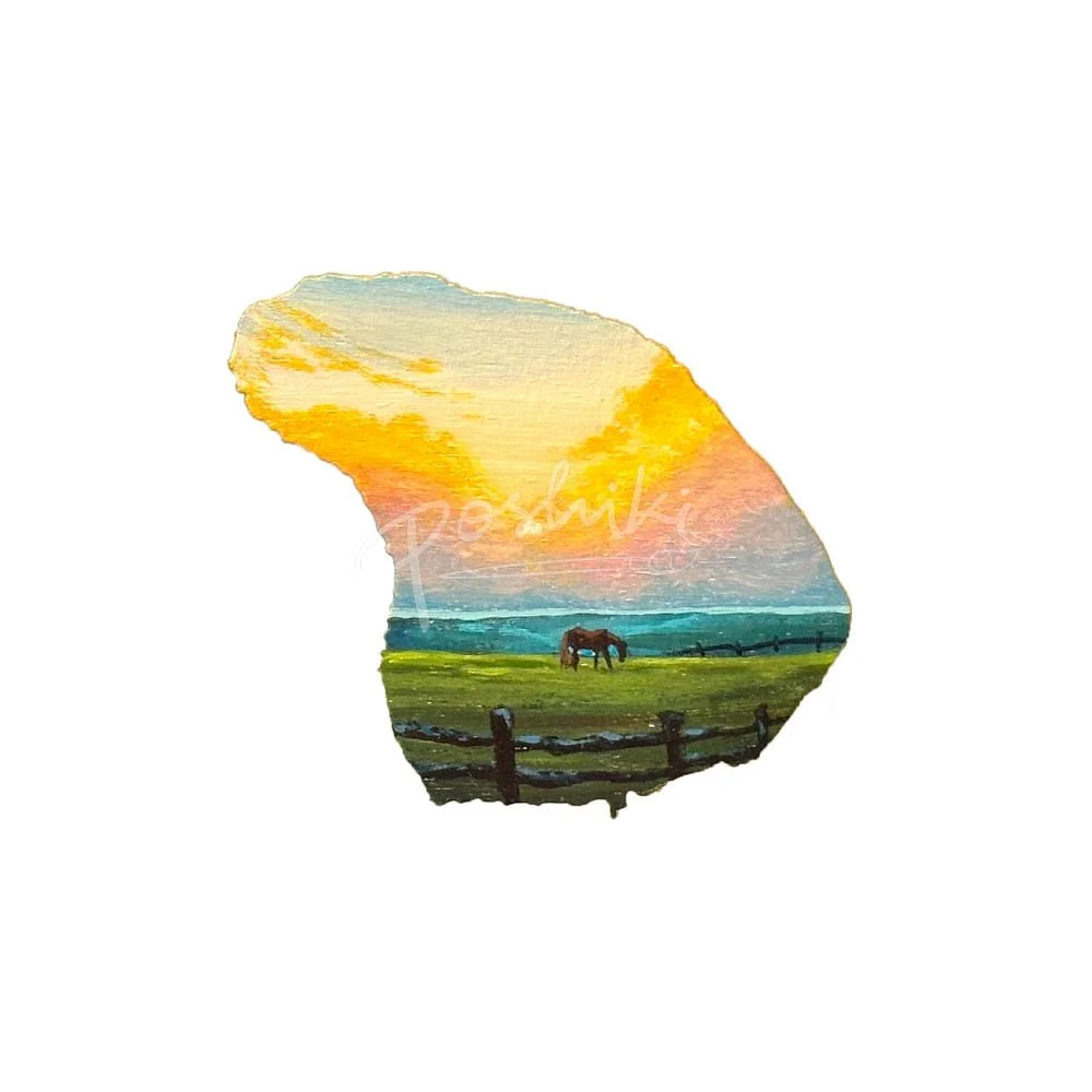 A hand-painted magnet in the shape of Lanai featuring a brown horse in a green pasture at sunset.