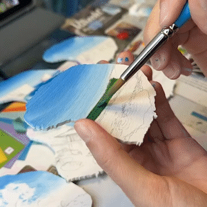 A timelapse of an artist painting a wooden magnet in the shape of the island of Lanai.