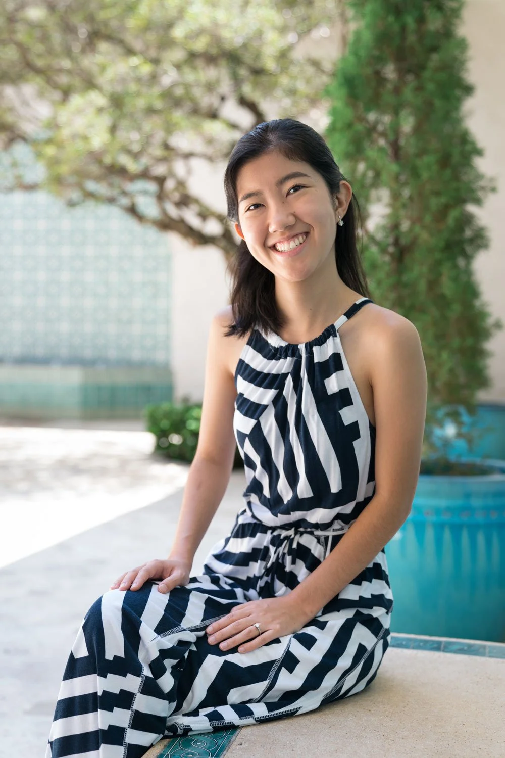 A girl in a white and black dress sits on a bench at the Honolulu Museum of Art.