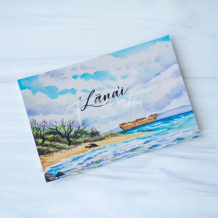 A watercolor landscape postcard of a monk seal on Shipwreck Beach with the word "Lānaʻi" in the middle.