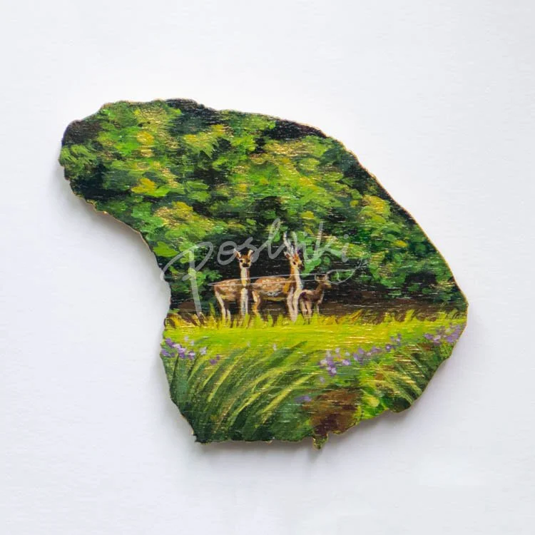 A hand-painted wooden magnet in the shape of Lanai, depicting three Axis deer.