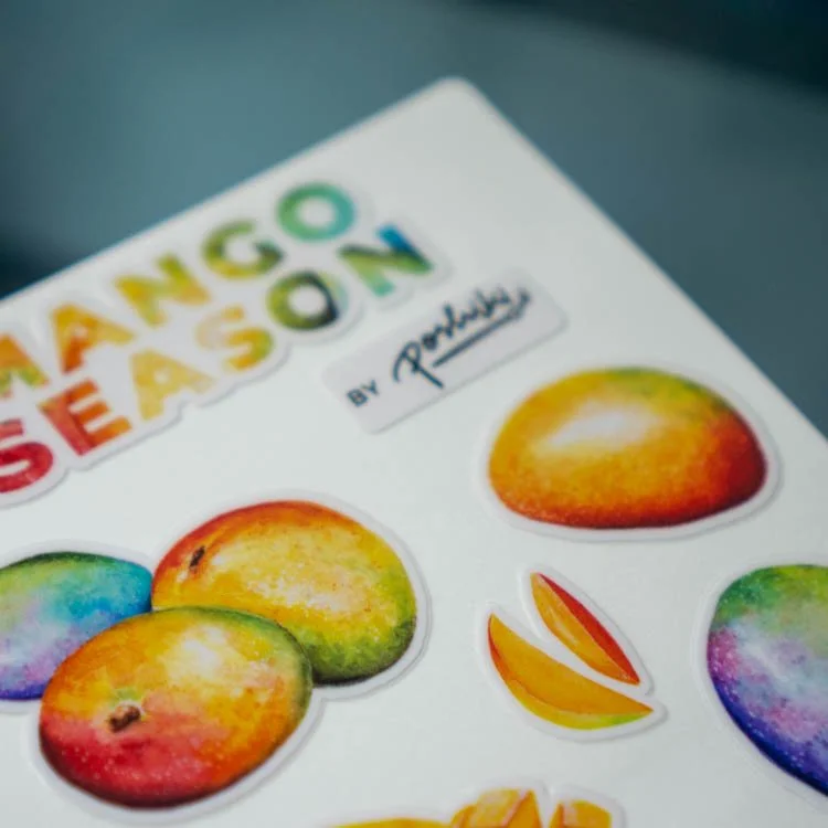 A close-up of a vinyl sticker sheet of watercolor mango illustrations.