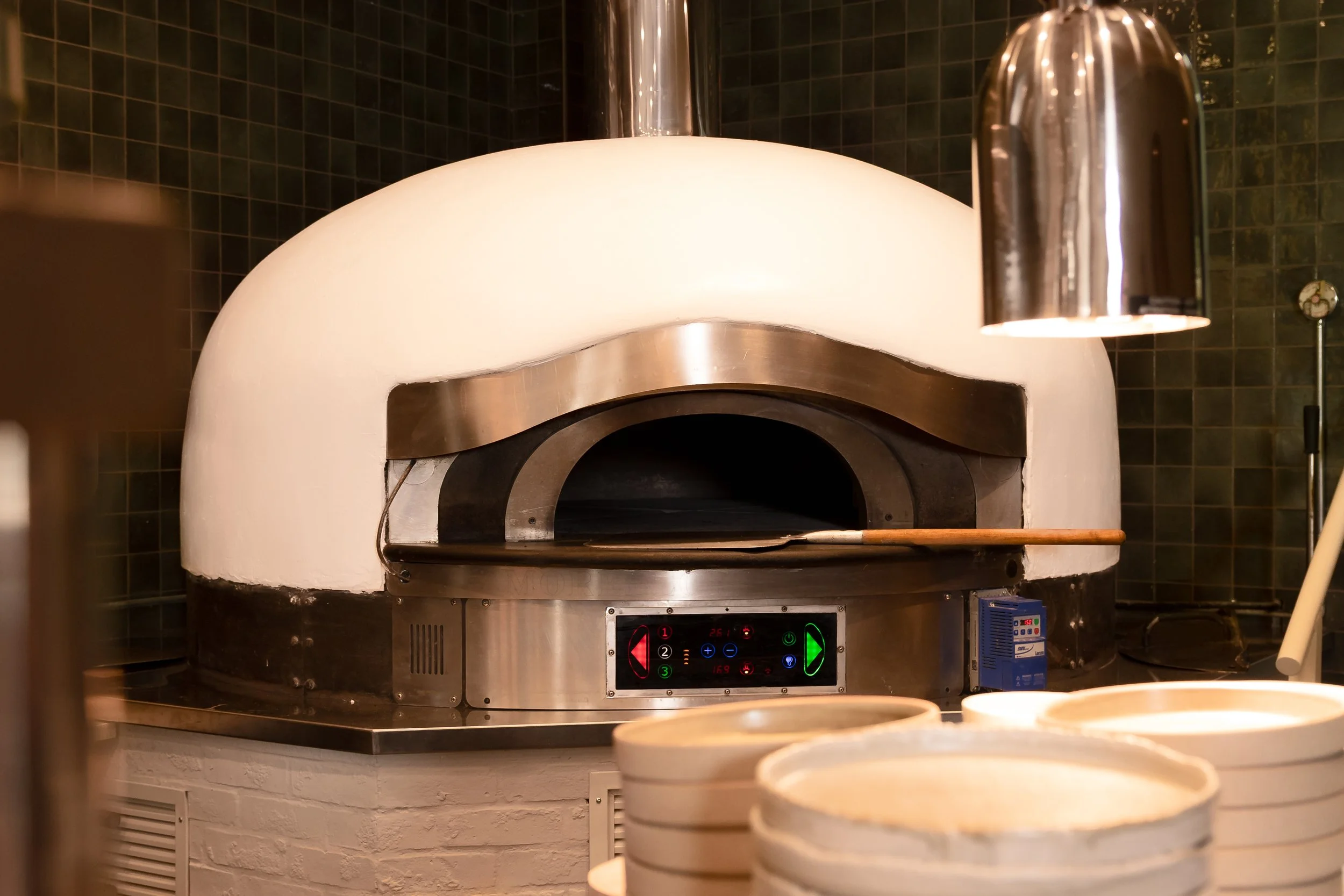 A commercial pizza oven with a white dome and stainless steel accents.