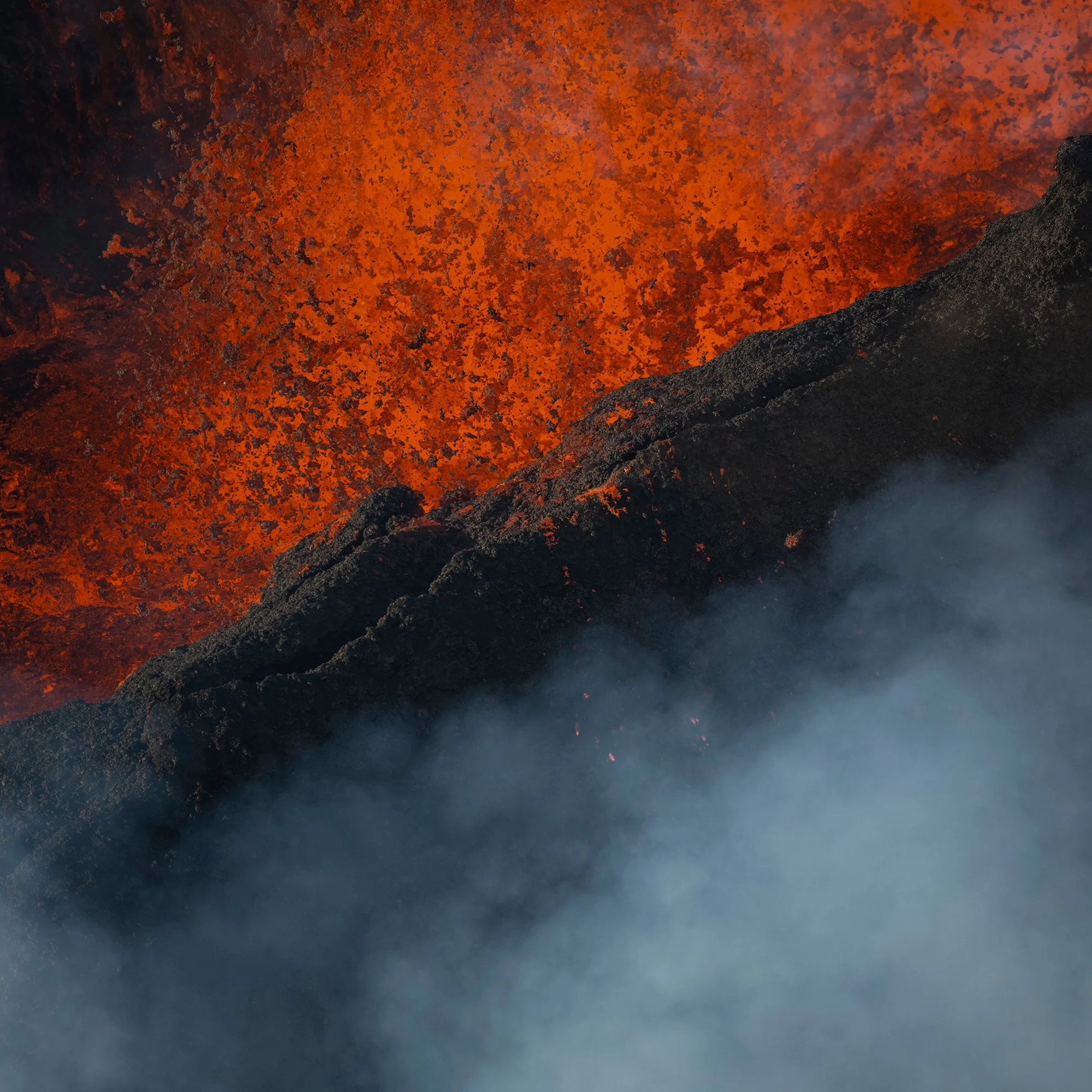A close-up of flowing lava with bright orange and red colors, accompanied by billowing smoke.