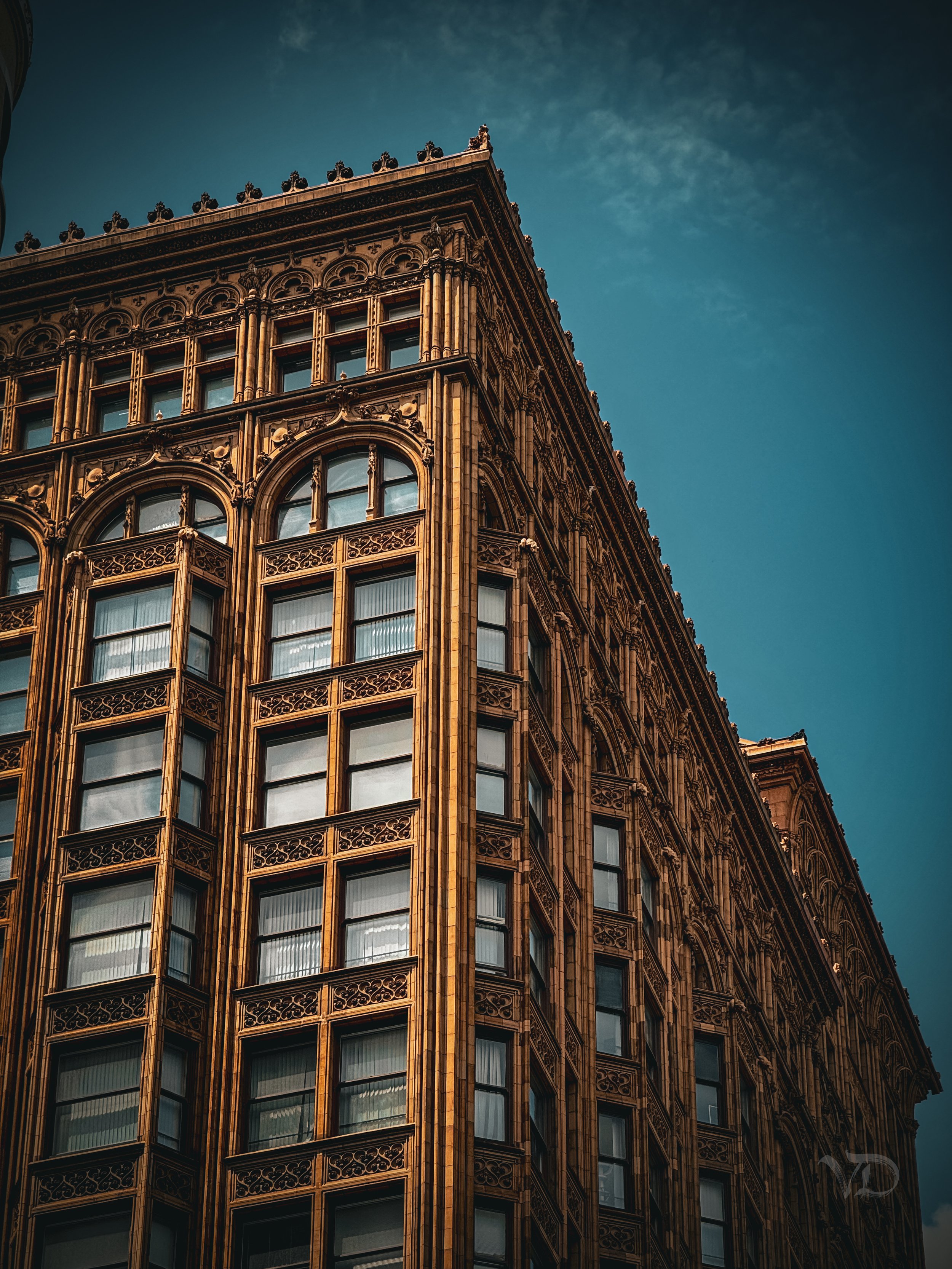 A tall ornate building with arched windows and decorative details, set against a blue sky.