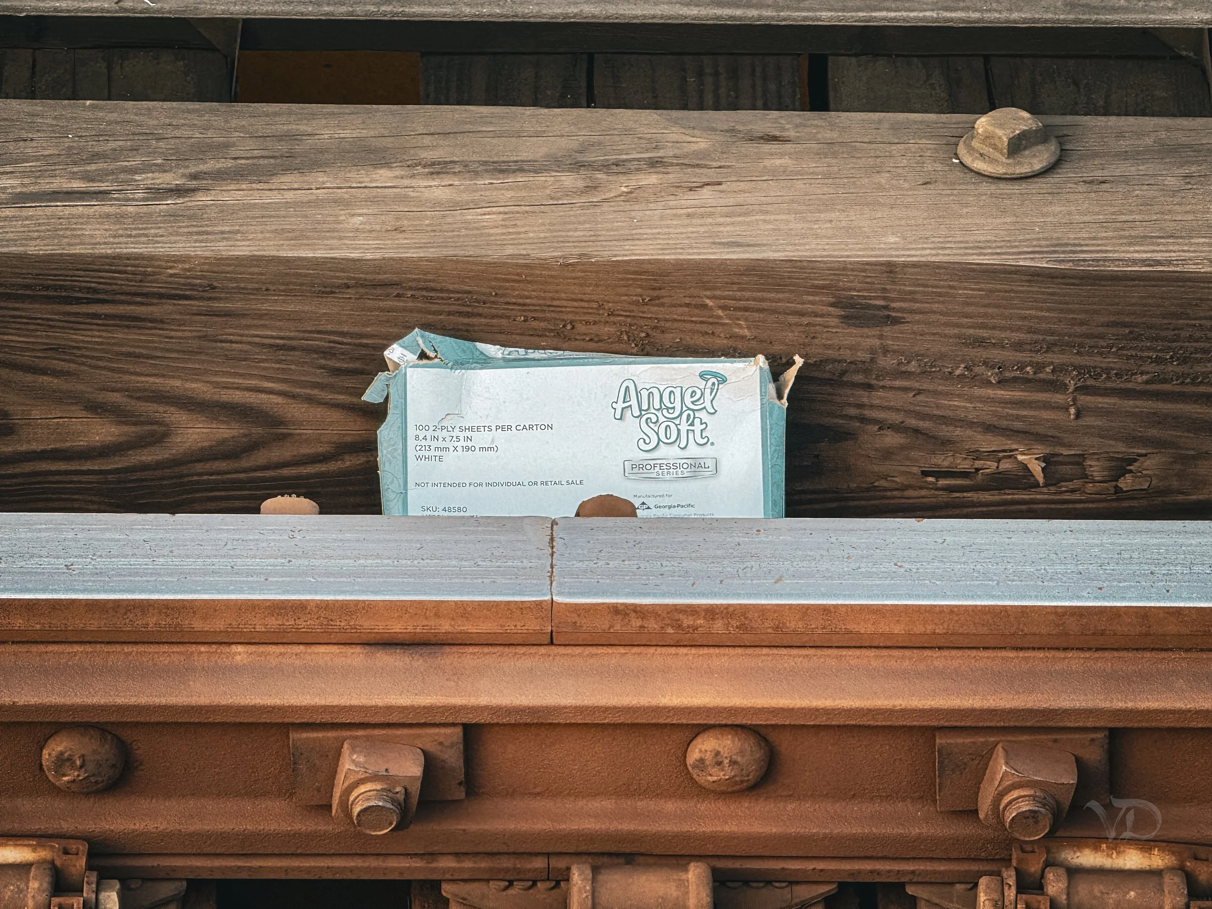 Close-up view of a wooden and metallic structure with a torn package of Angel Soft toilet paper placed in the open space.