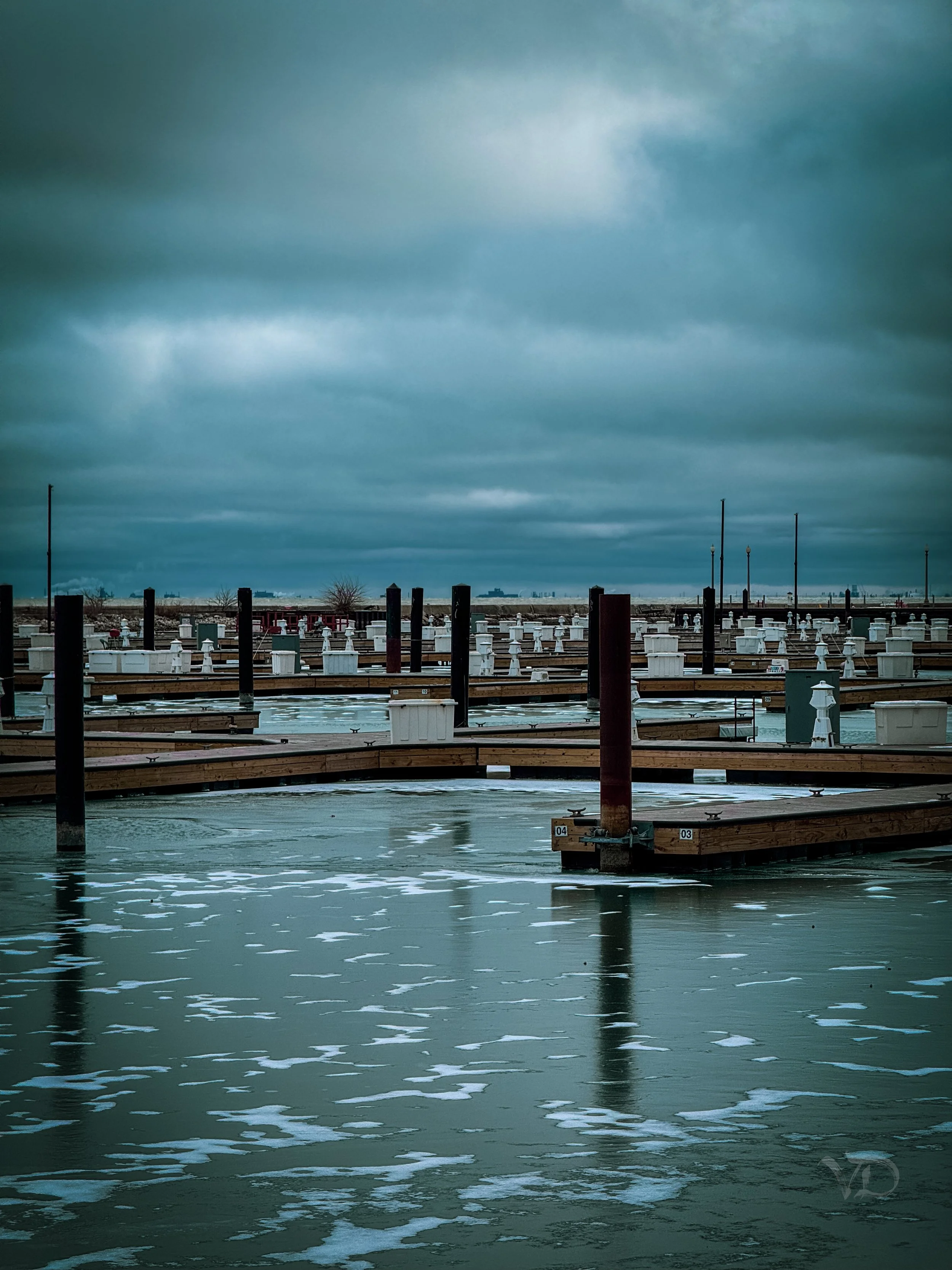 An empty marina with wooden docks under a cloudy, overcast sky.