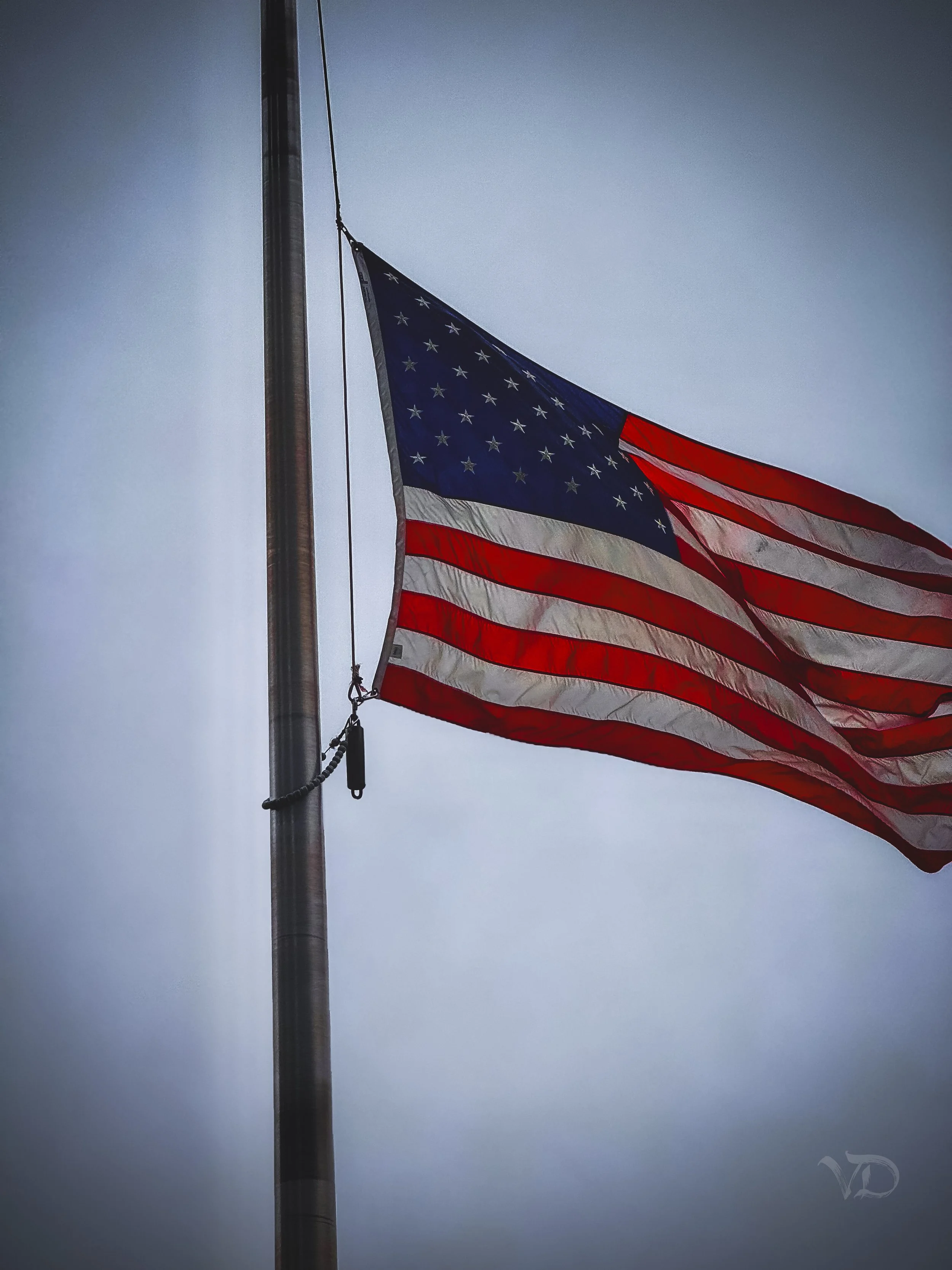 American flag flying on a flagpole against a gray sky.