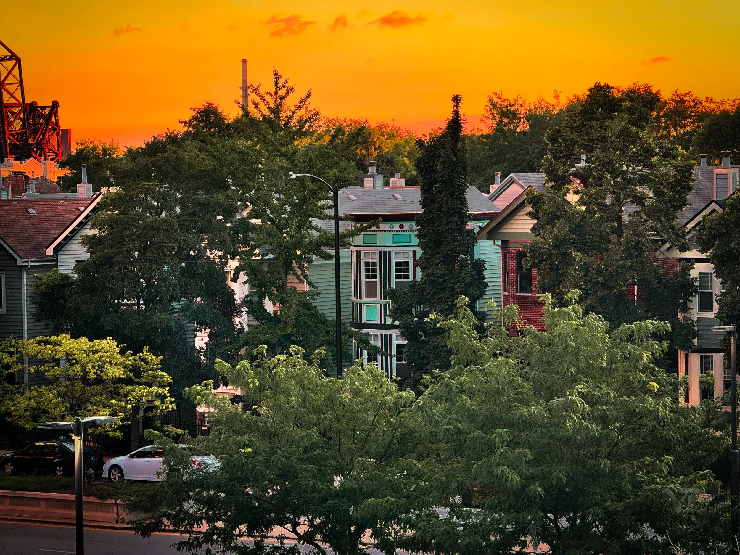 Sunset over a neighborhood with colorful houses and trees.