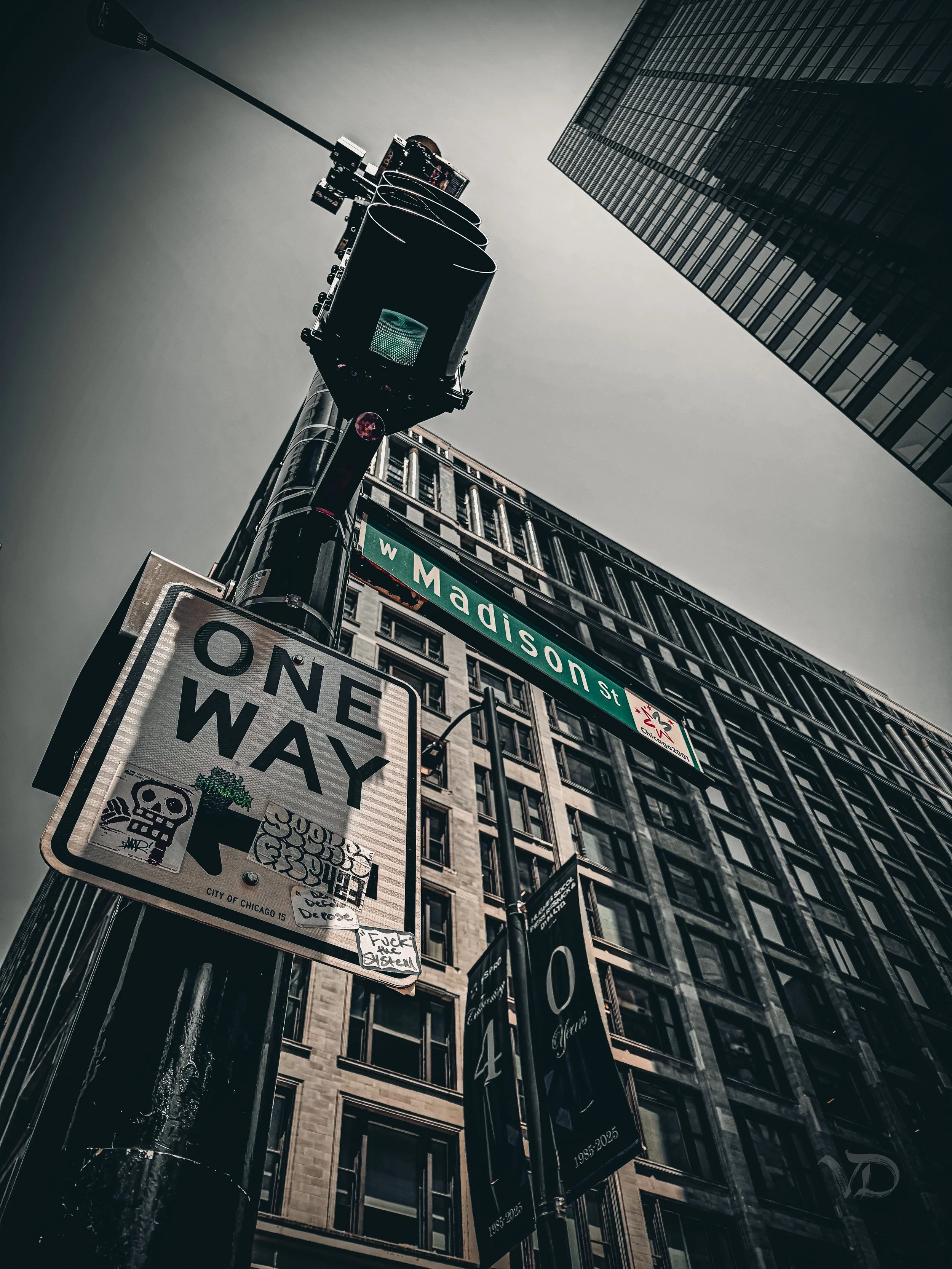 Low-angle view of a street corner with a traffic light, street signs for W Madison St and W Wacker Dr, and tall buildings in Chicago.