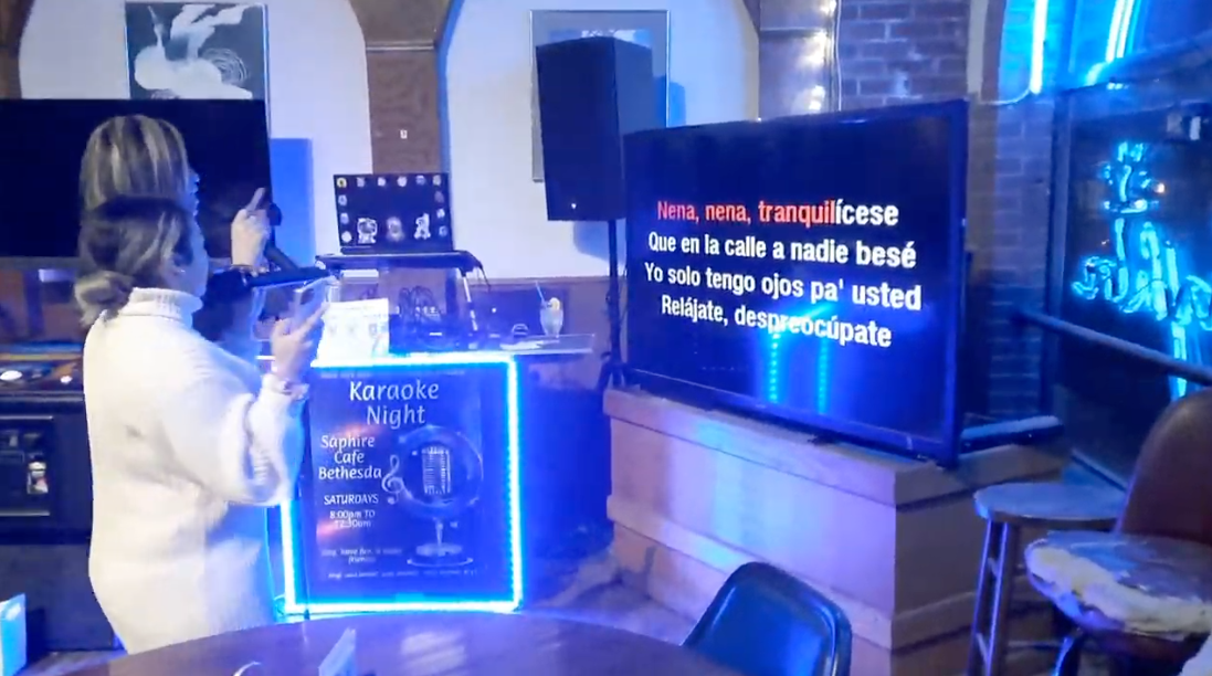 Singer performing under neon lights at Nikki NYX International Karaoke & Dance, showcasing a welcoming karaoke night with global music and a supportive audience.