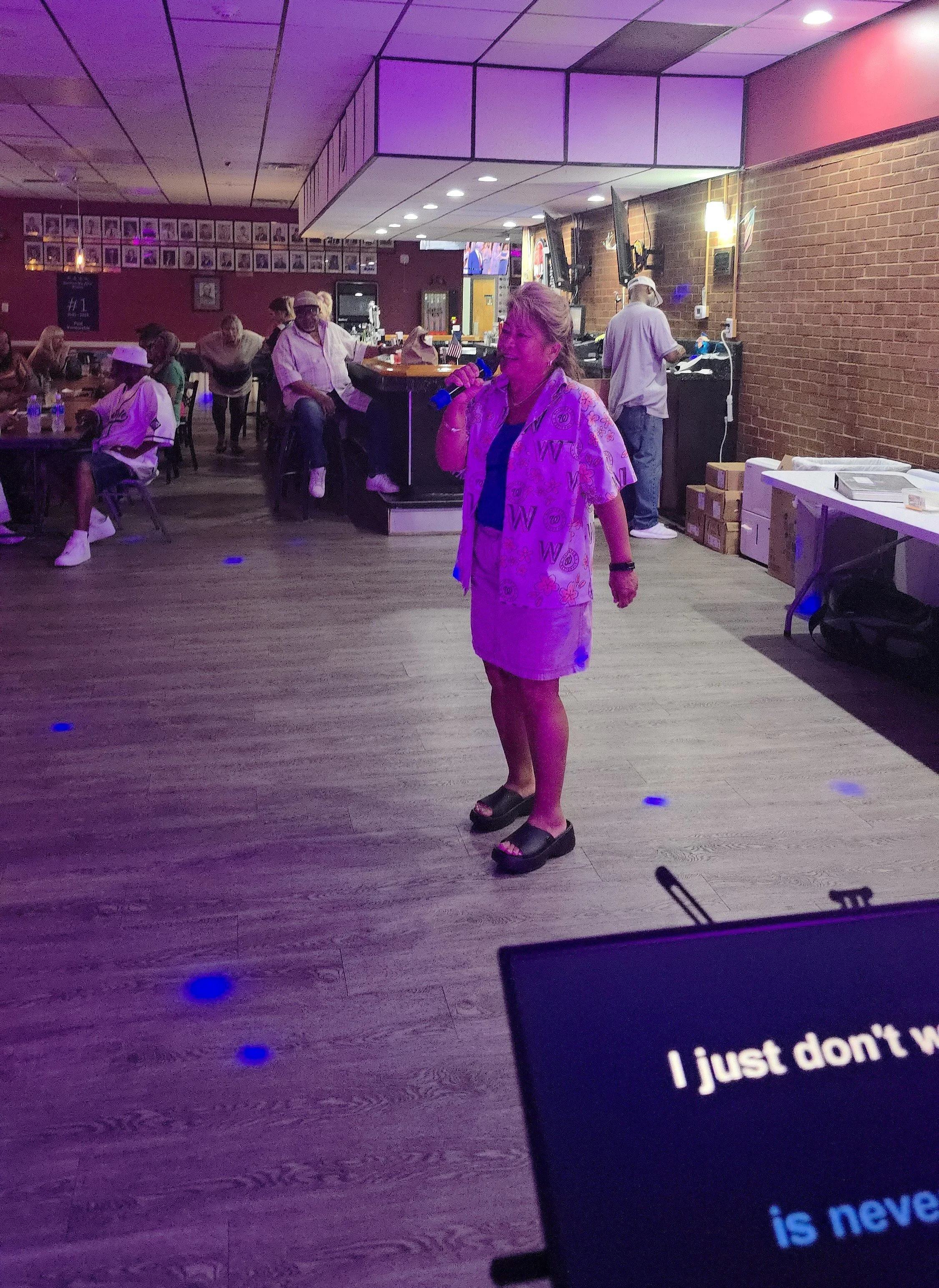 Singer performing at Nikki NYX International Karaoke & Dance with lyrics displayed on screen, showcasing an inclusive karaoke night where voices of all backgrounds are welcomed.