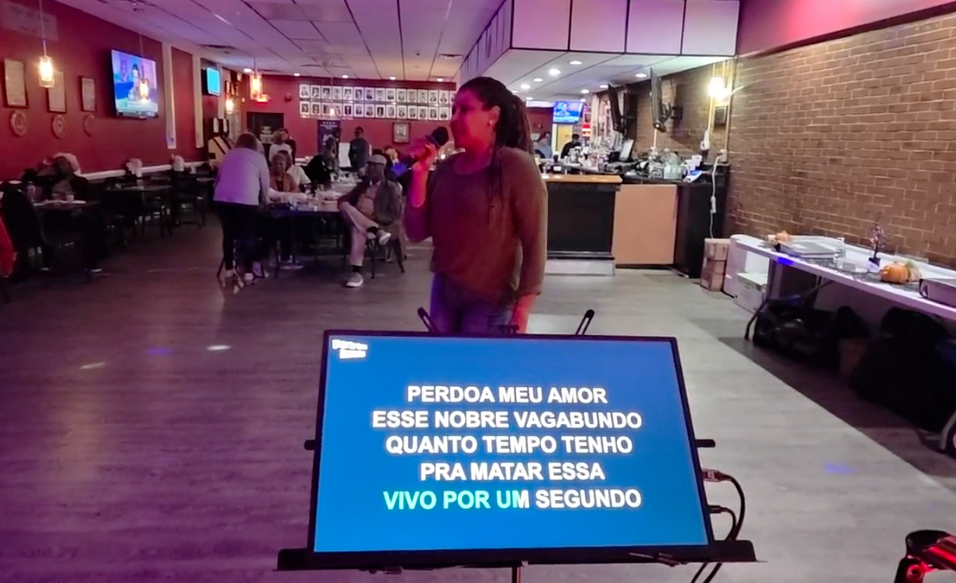 Singer performing at Nikki NYX International Karaoke & Dance with lyrics displayed on screen, showcasing an inclusive karaoke night where voices of all backgrounds are welcomed.