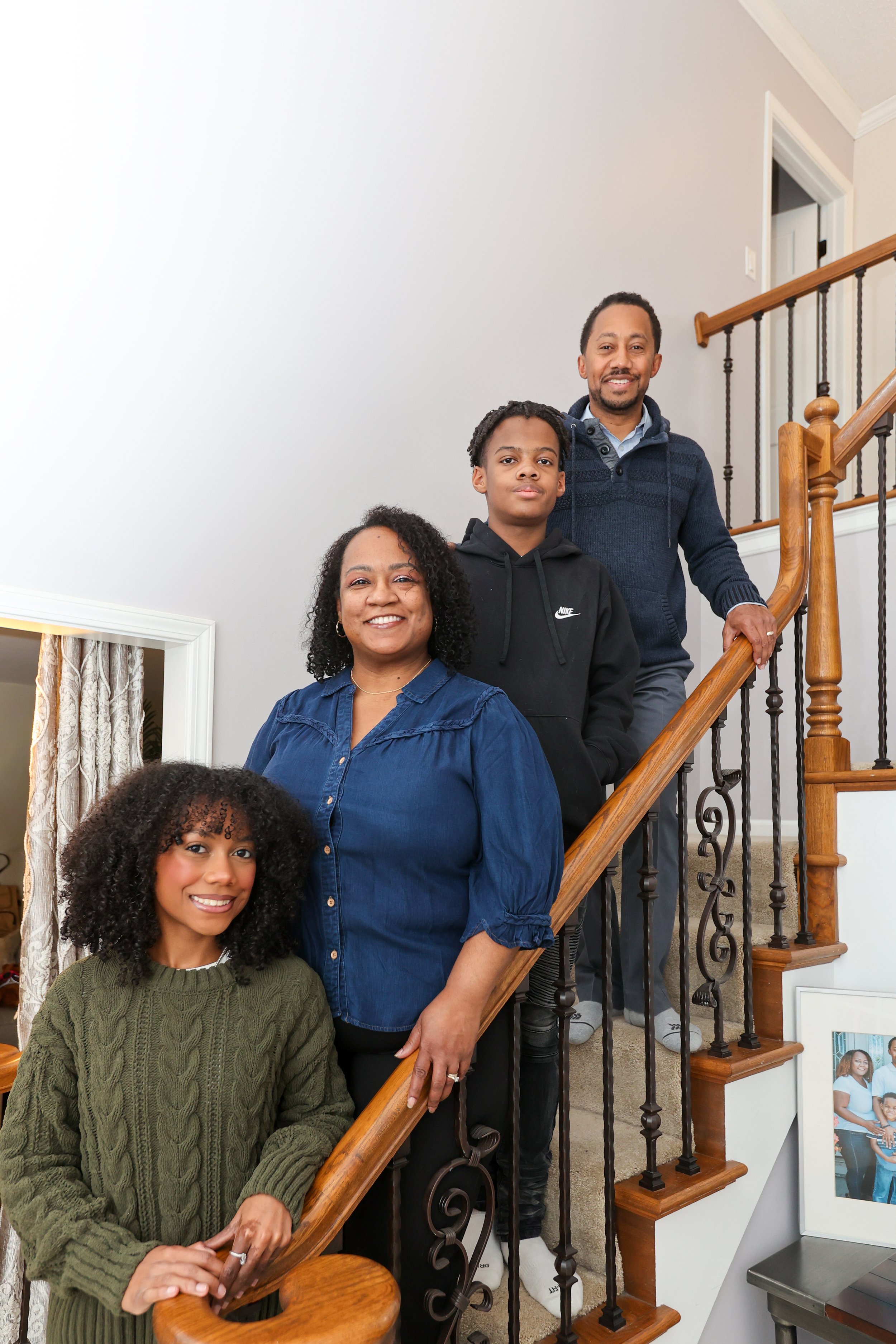 A family of five standing on a staircase during a family gathering or event, smiling at the camera with a white wall in the background.