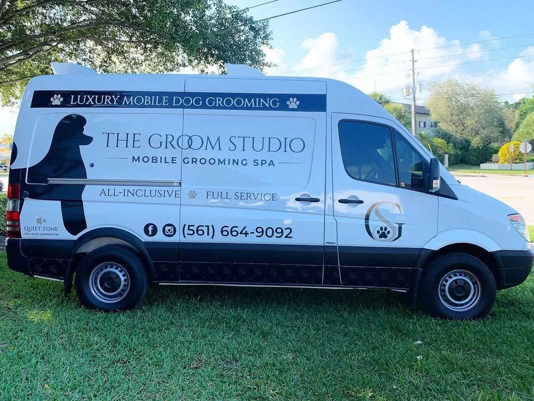 A white van wrapping by finyl design with black and blue graphics and text advertising The Groom Studio, a mobile grooming spa for dogs. this is a commercial wrap in pal beach by finyl desing