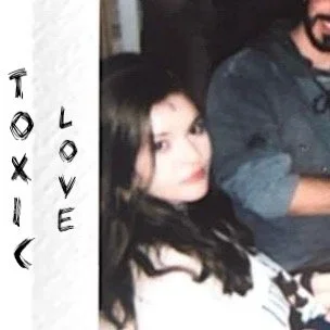 MereJane with dark hair and makeup sitting next to a man with a beard, both sitting next to a white sign with black text that reads 'Toxic Love' and a skull illustration.
