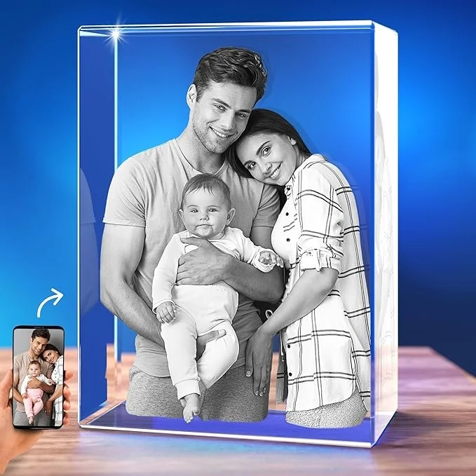A 3D crystal photo frame displaying a black and white picture of a happy family with a man, woman, and a baby, with a smartphone capturing the image.