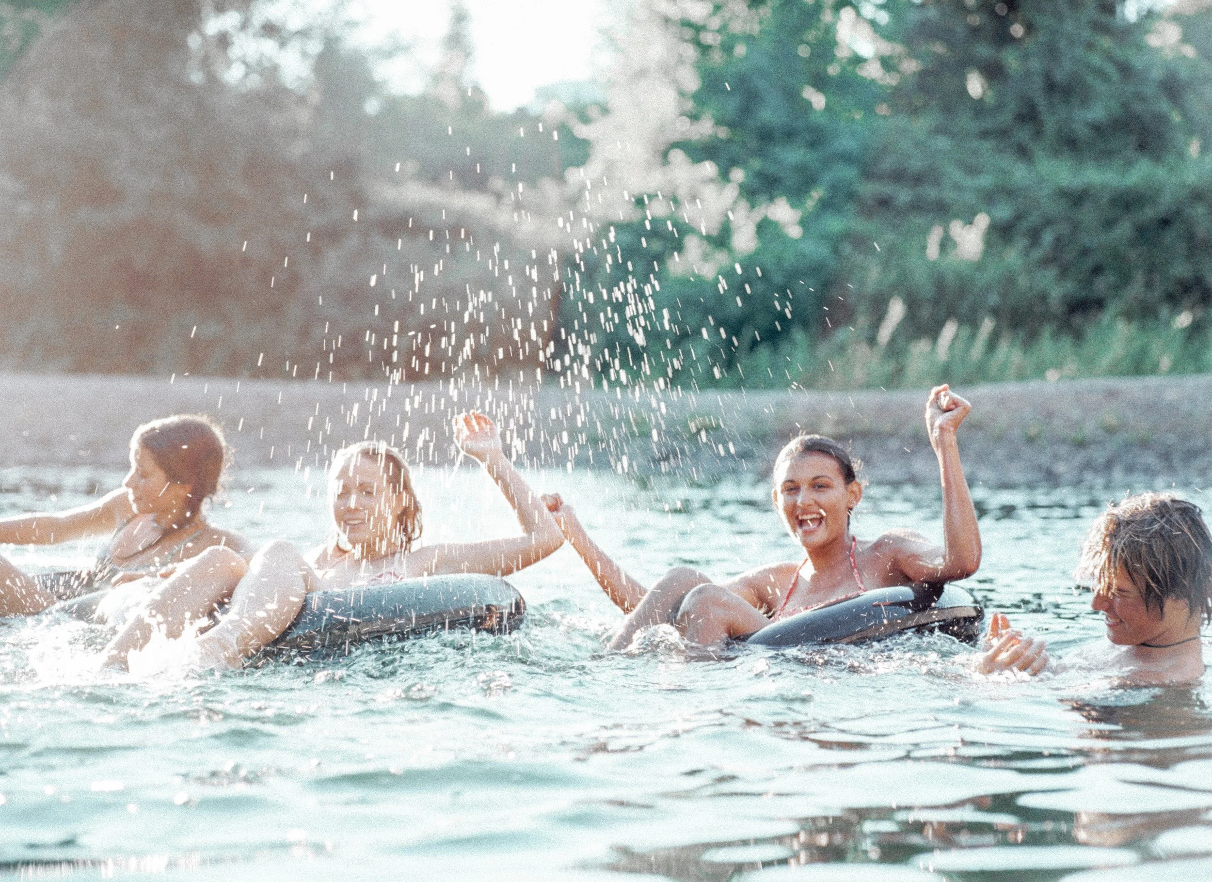Group of women river tubing on a river in Texas for a bachelorette party in the summer and enjoying the water and summer fun.