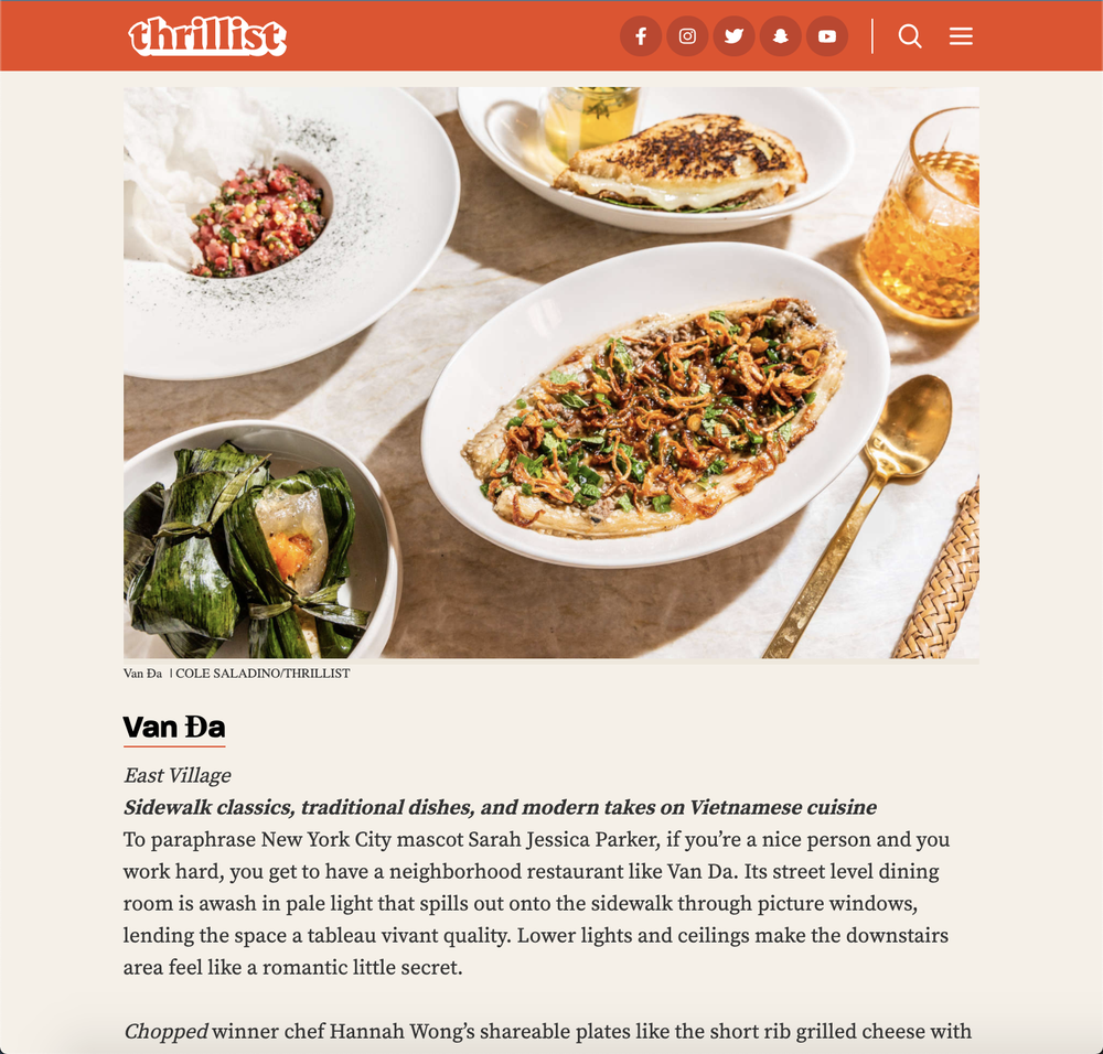 Variety of Vietnamese dishes on a table, including grilled meat, rice wrapped in leaves, and a salad, with a golden spoon and cocktail jar visible.