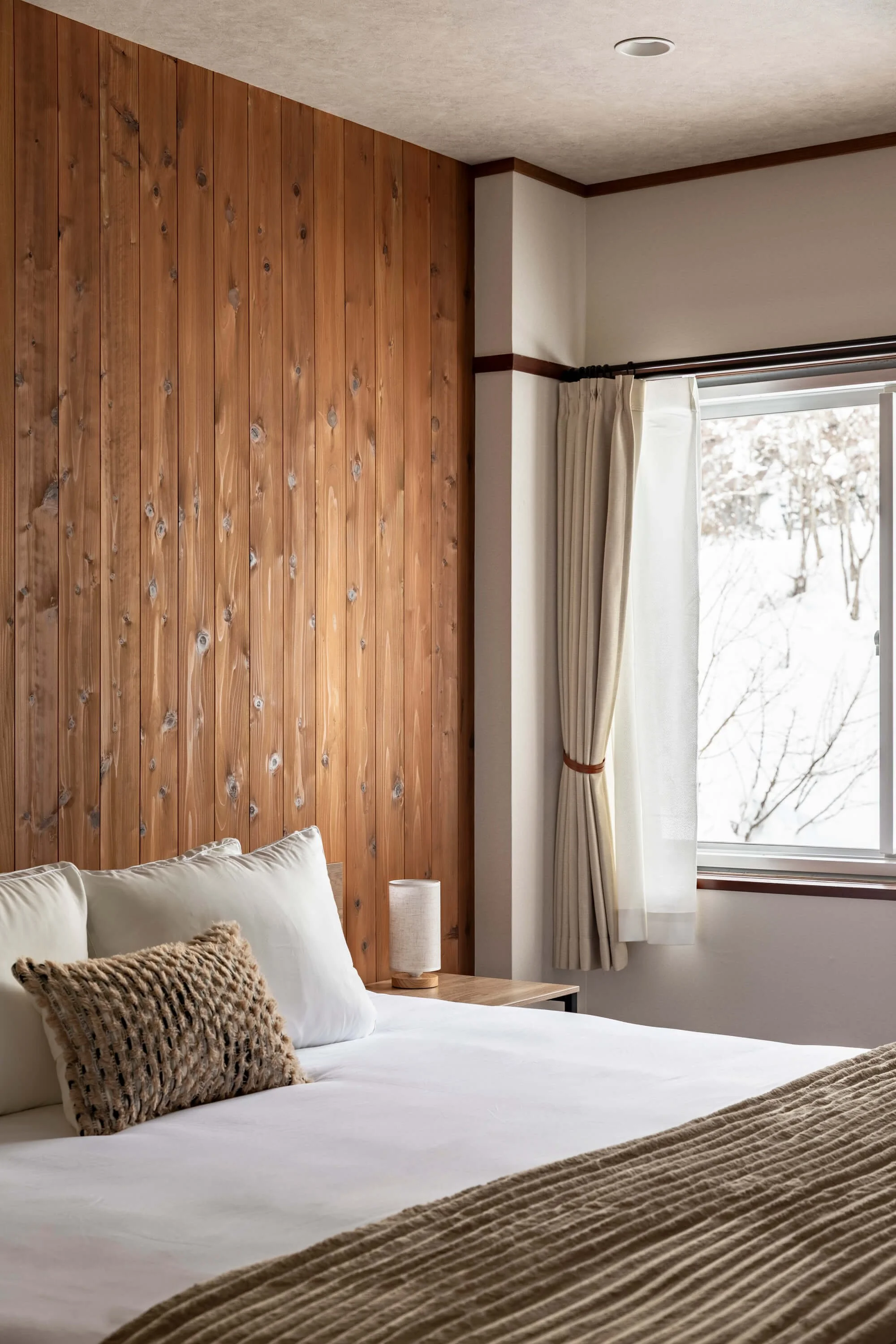 A freshly made bed and light streaming in a window