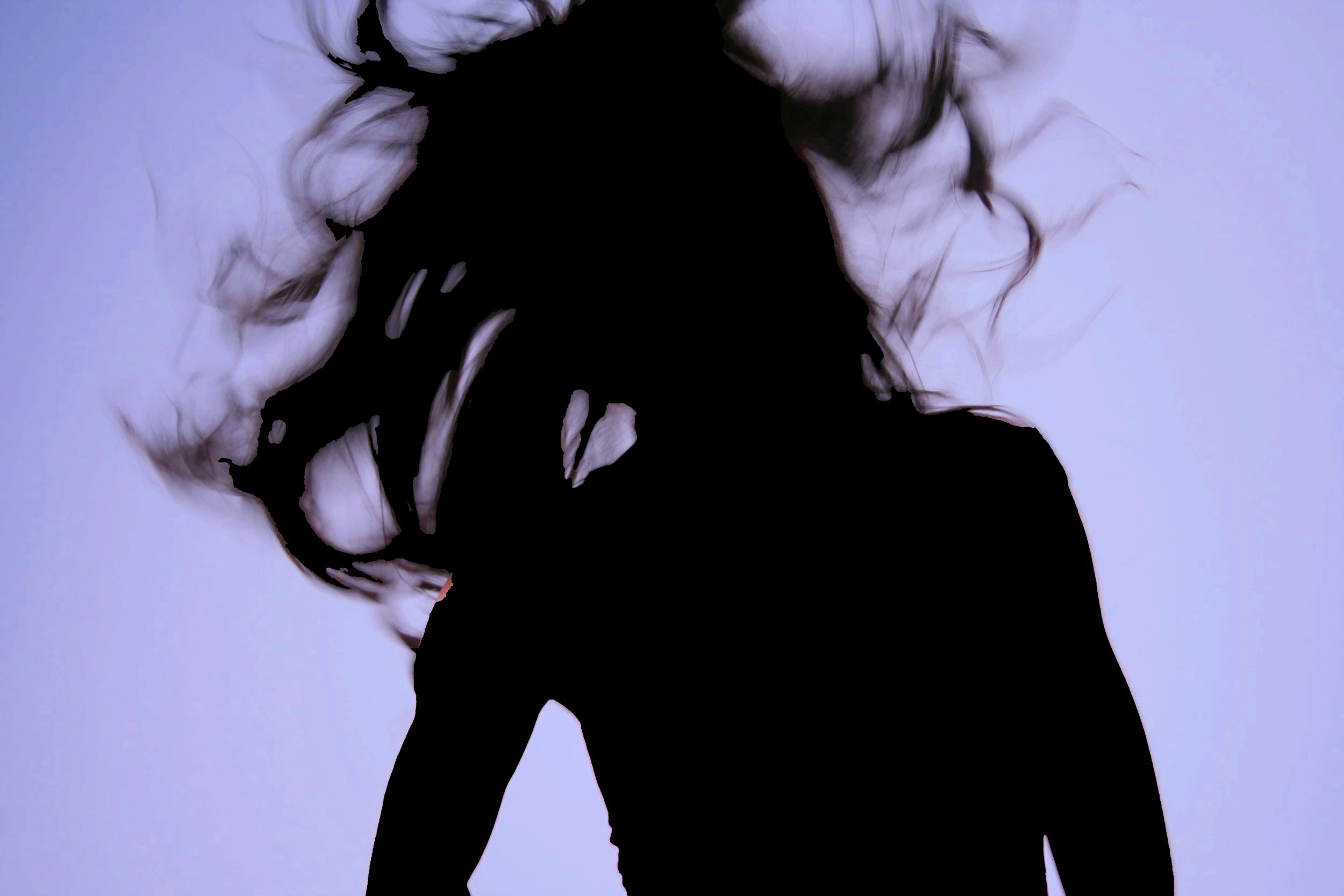 Silhouette of a woman with curly hair against a light background.