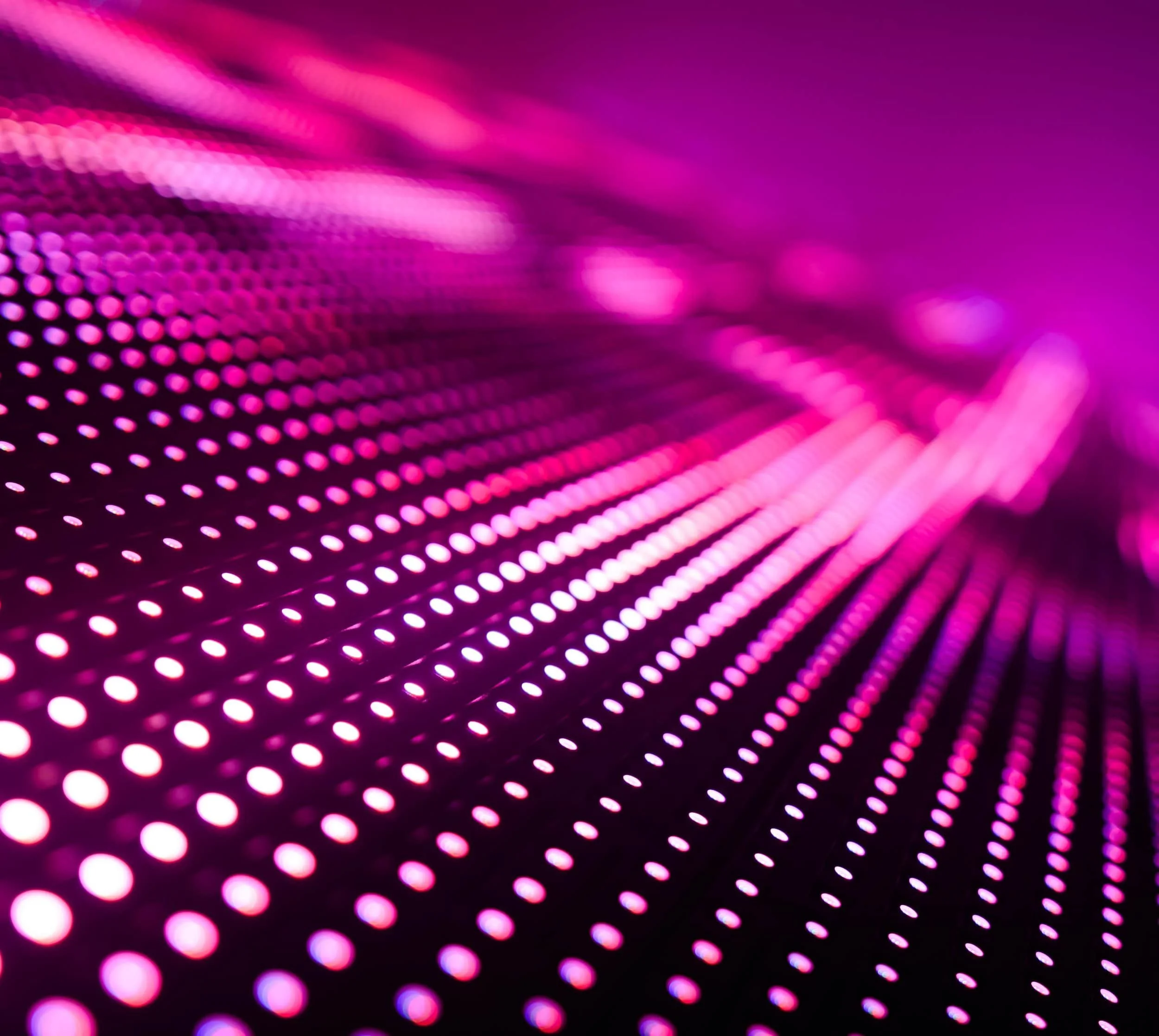 Close-up of pink and purple LED lights on a dark surface, creating a futuristic pattern.