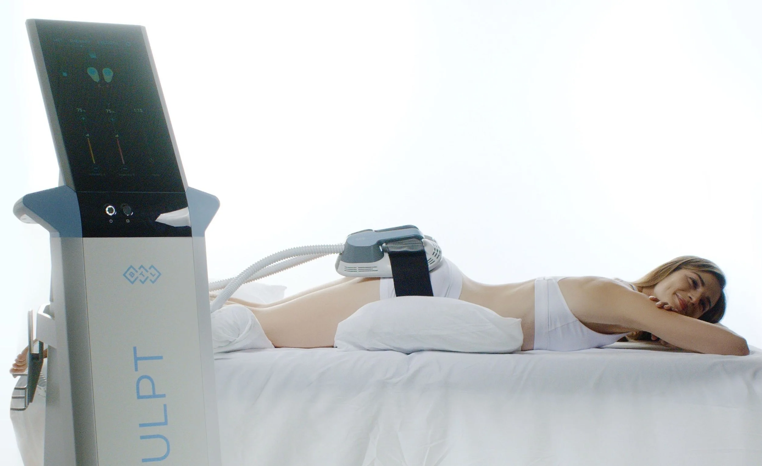 Woman lying on a medical bed undergoing a high-tech treatment with a large machine connected to her abdomen.