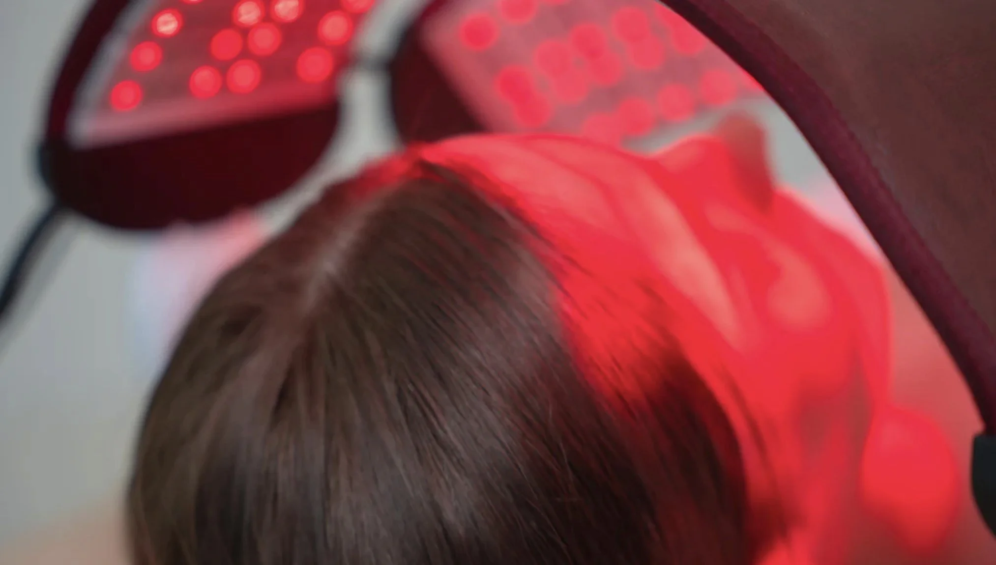 Close-up of a person with brown hair wearing red headphones, with a blurred background.