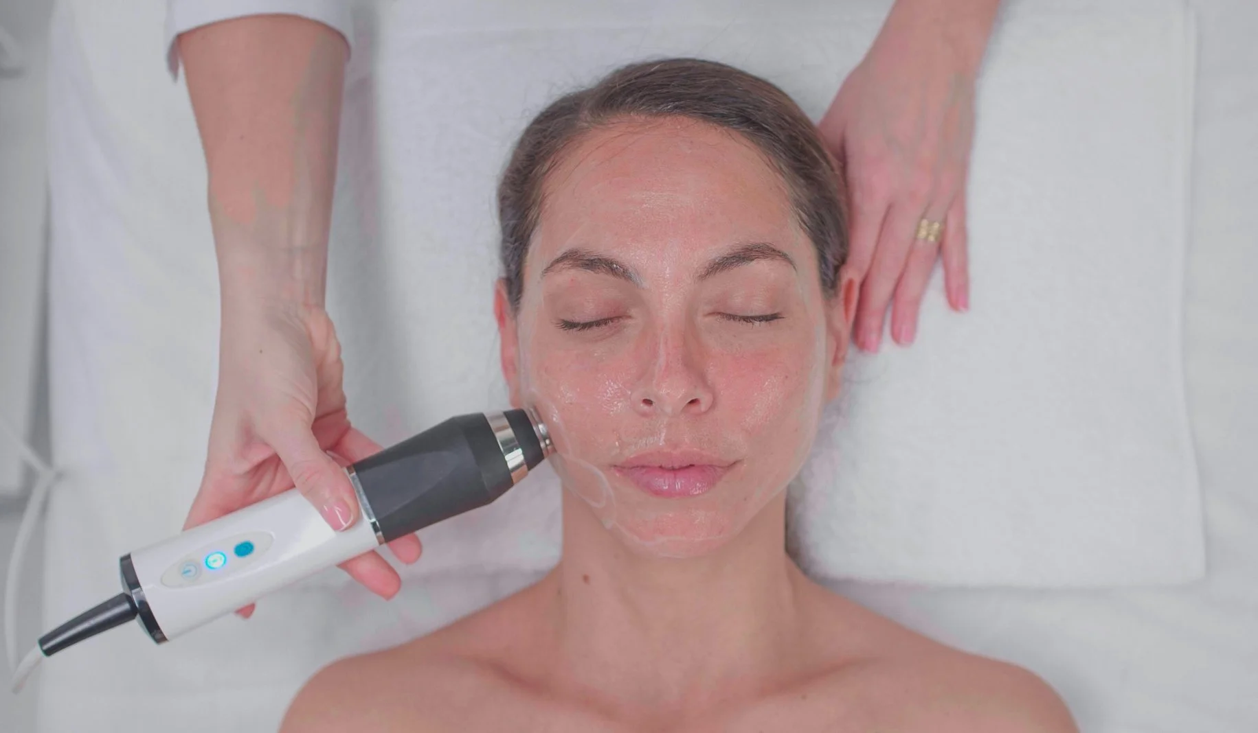 A woman receiving a facial treatment using a handheld device in a spa or clinic setting