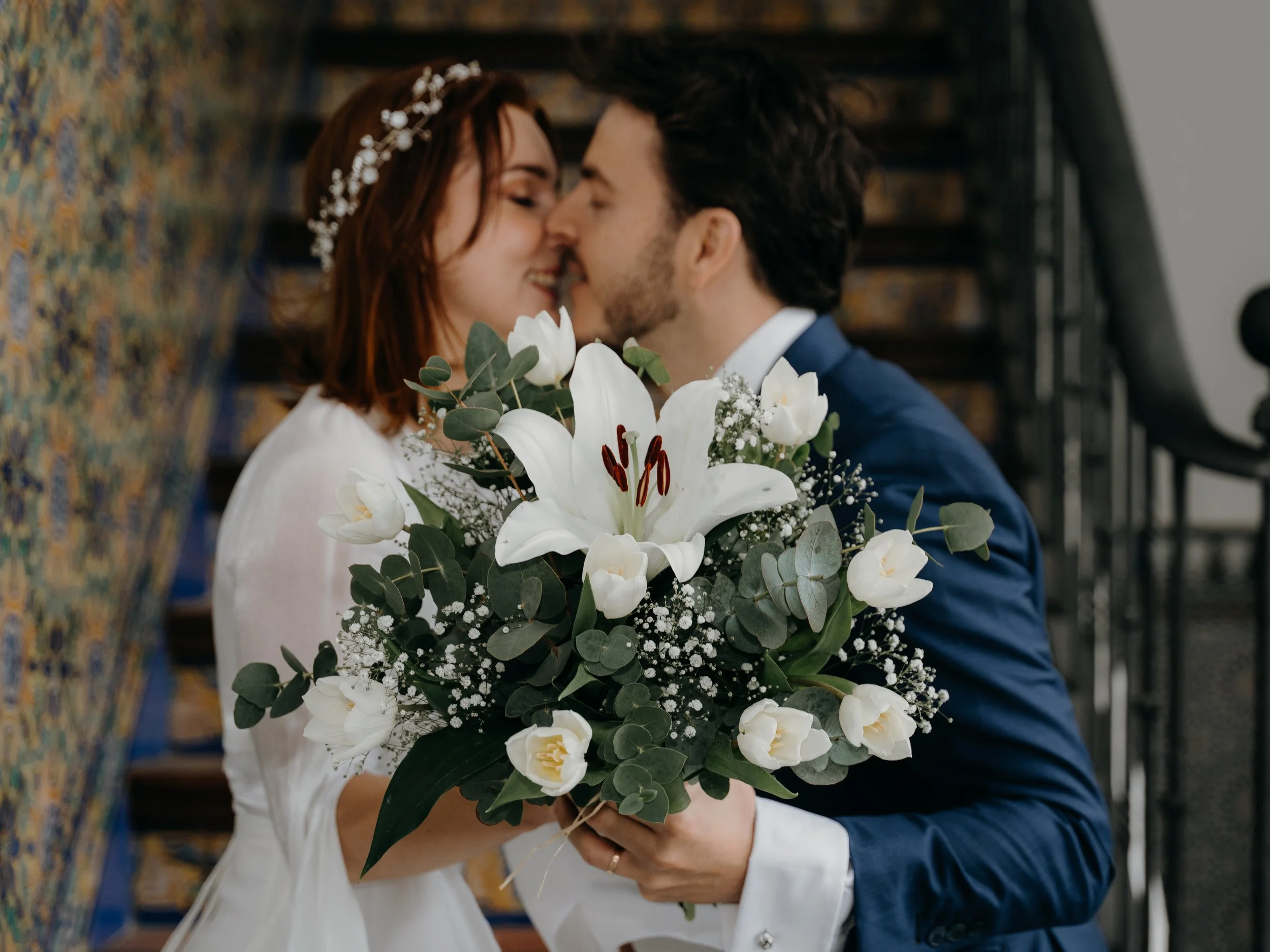 Pareja de novios besándose con ramo de flores blancas en una boda. Estudio fotográfico especializado en bodas exclusivas de alto standing. Para novios exclusivos y lugares con encanto