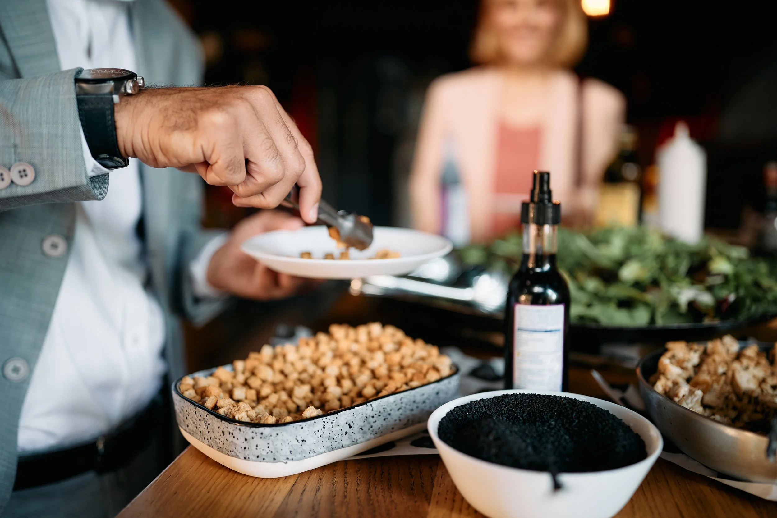 Persona sirviendo comida en un restaurante con diversos ingredientes en la mesa.