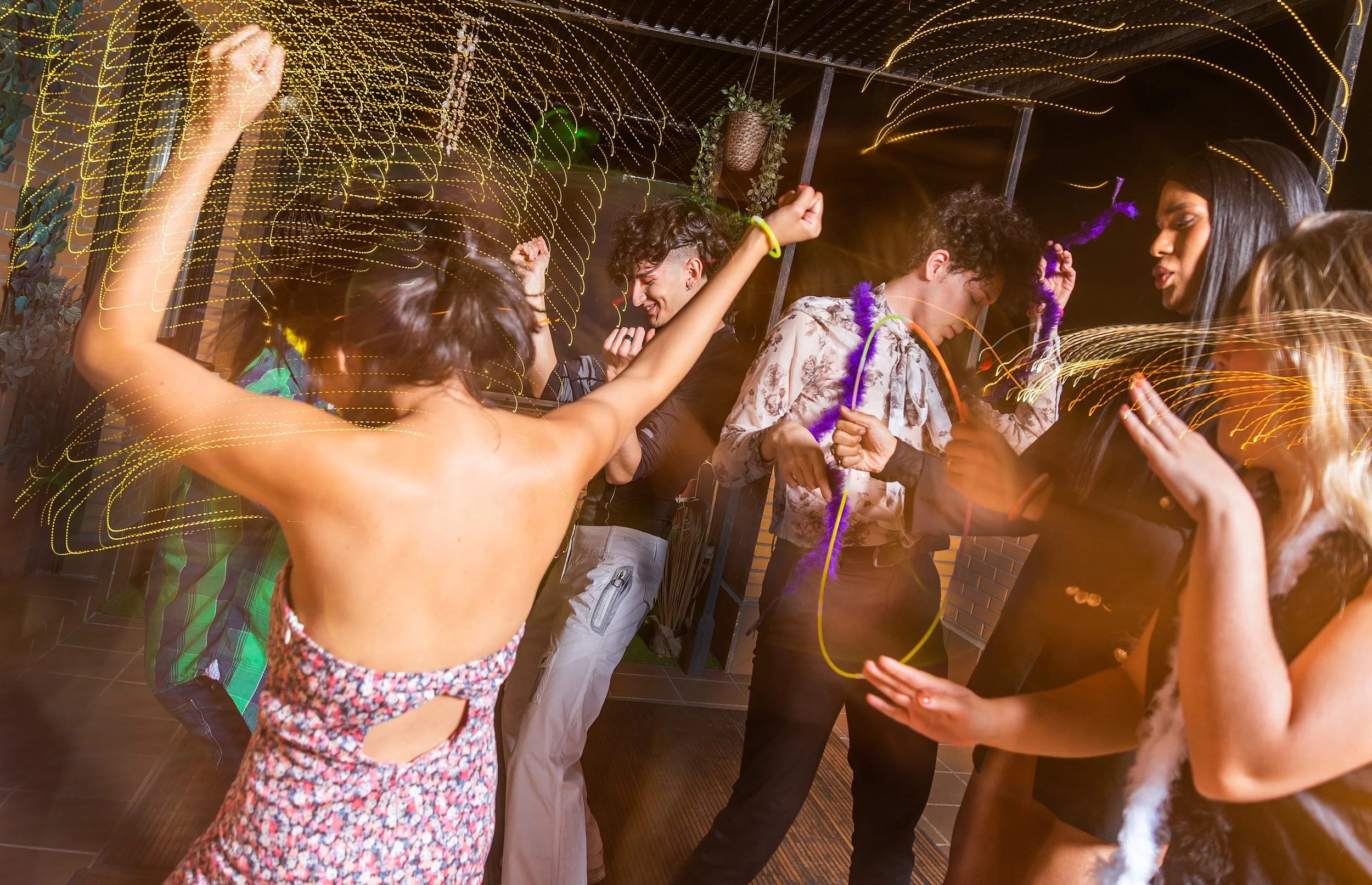 Personas bailando y disfrutando en una fiesta nocturna con luces y decoración festiva.