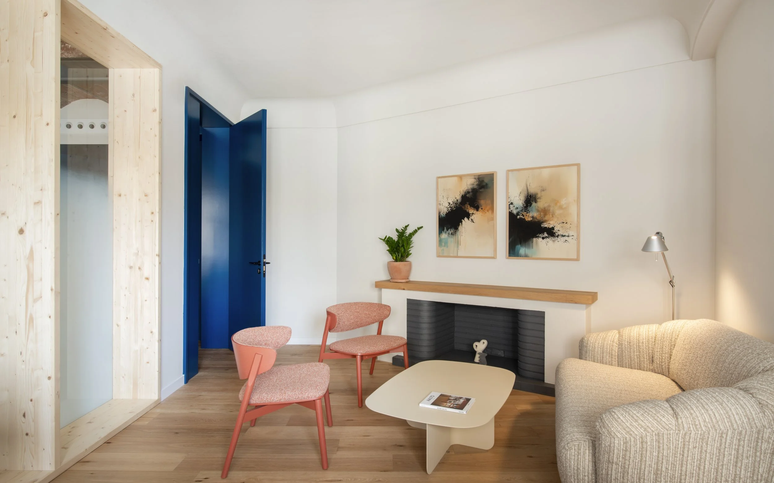 Vista general de sala con puerta azul, obras de arte y vegetación en Vértigo Vida, Barcelona. Interiorismo que aleja la estética clínica, proyecto de Escabeche Studio.