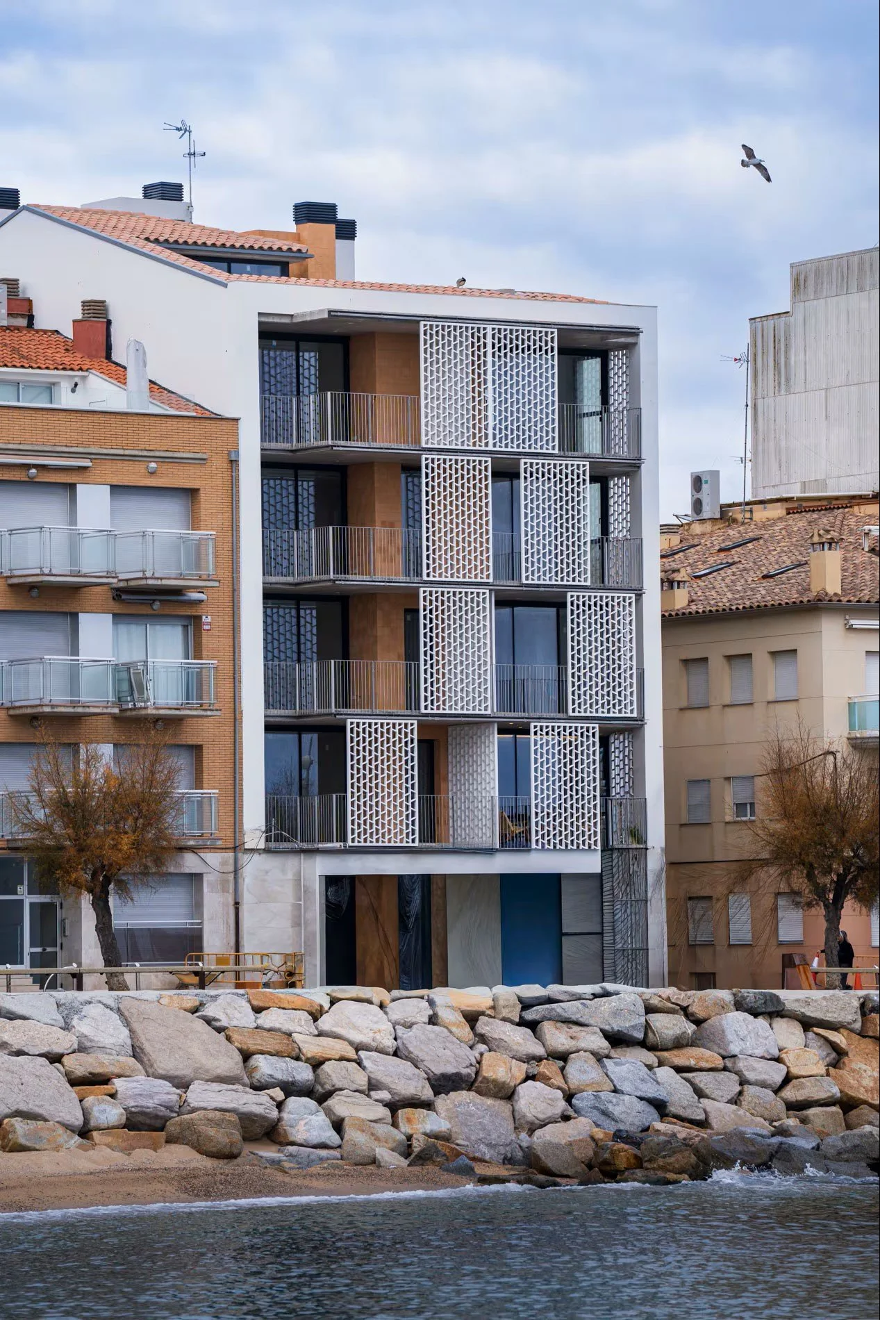 Detalle de fachada de Sorra Mar i Cel con celosía geométrica y balcones con vistas. Acabados exteriores del complejo de apartamentos turísticos en la Costa Brava. Escabeche Studio.