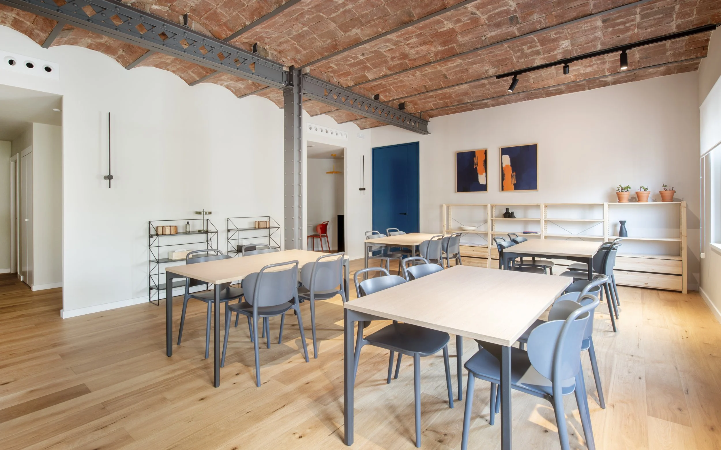 Sala de trabajo o talleres de Vértigo Vida con mesa grande, sillas y techo de vigas. Espacio funcional en centro terapéutico de Barcelona, proyecto de Escabeche Studio.