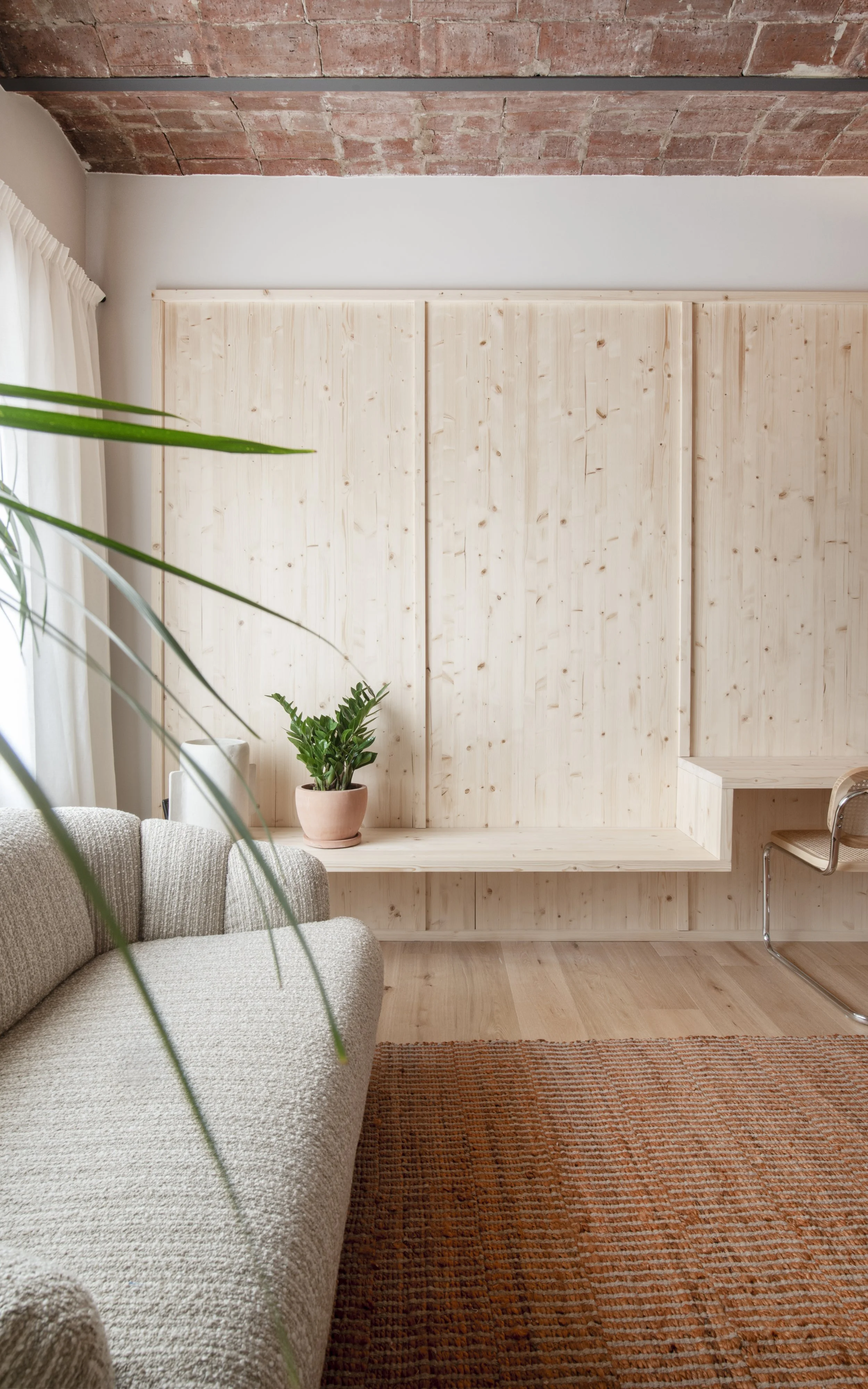 Rincón de descanso con banco de madera, vegetación y luz natural en Vértigo Vida, Barcelona. Diseño interior terapéutico por Escabeche Studio.