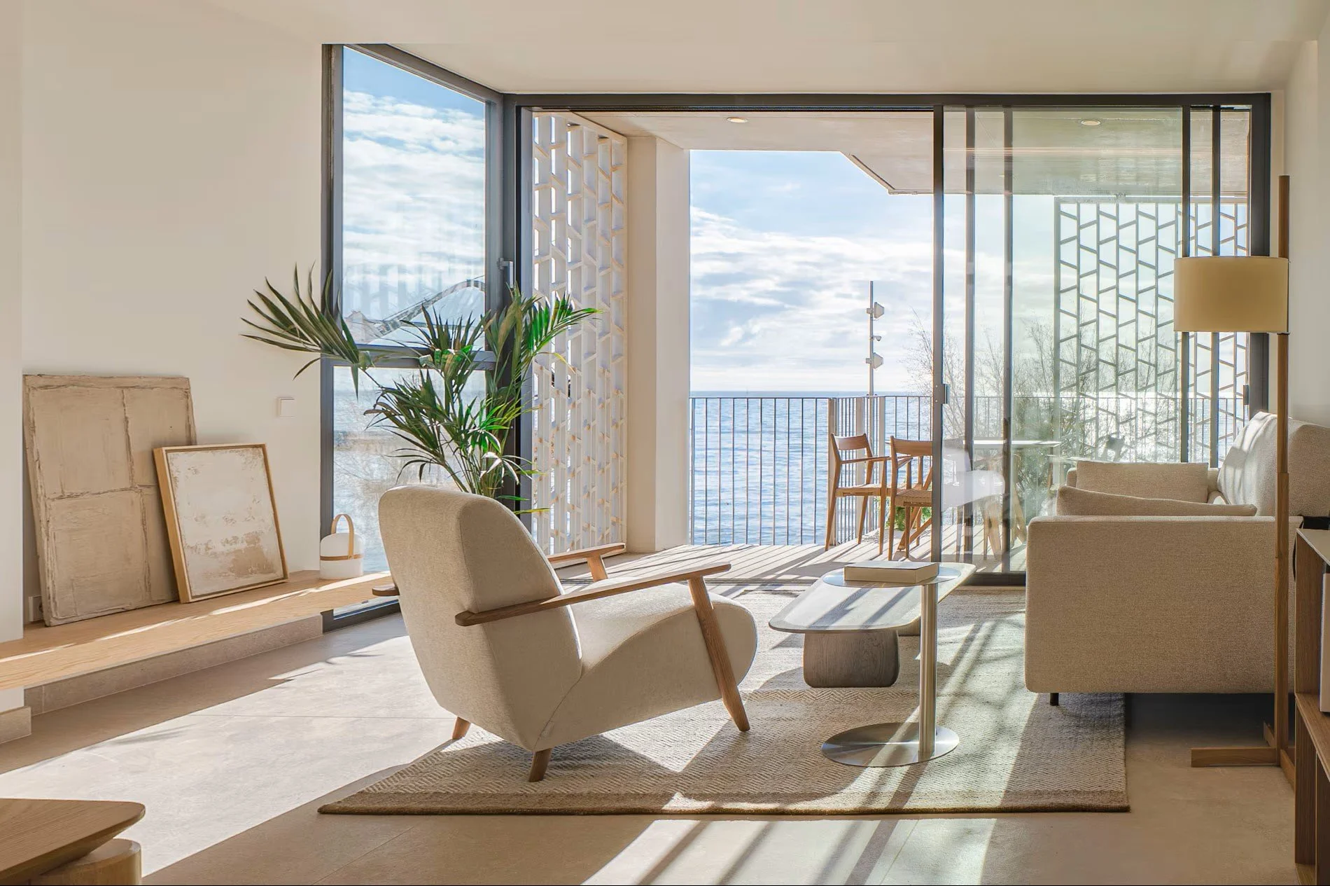 Salón de apartamento turístico en Sorra Mar i Cel con sillón blanco y vistas panorámicas al mar. Interiorismo mediterráneo luminoso para hospitality en la Costa Brava. Escabeche Studio.